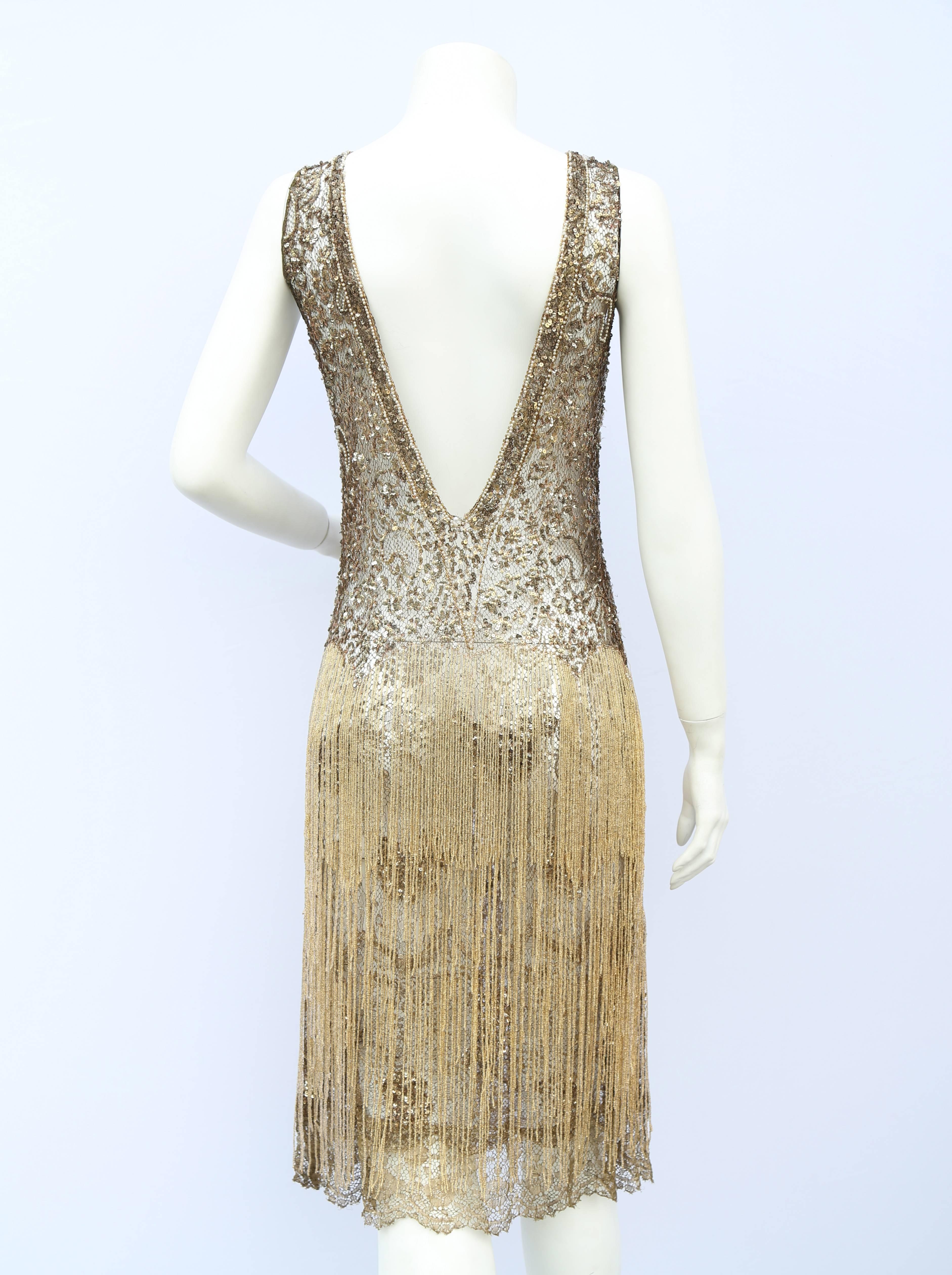 A vintage 1920s reworked flapper dress an original 20s bodice in gold lace with sequin and bead work throughout and a individual gold beaded strand skirt from the waist down a high neck and a low v shaped back 

size uk 6 pull on

Measurements