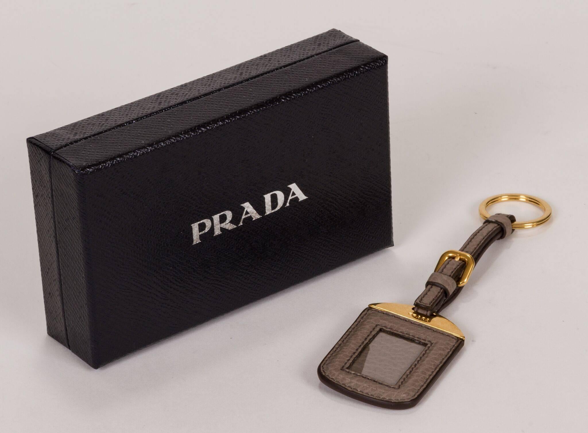 Nouveau porte-clés et porte-noms Prada 2014. Cuir gris et matériel de couleur or. Livré avec la boîte et l'étiquette d'origine.
