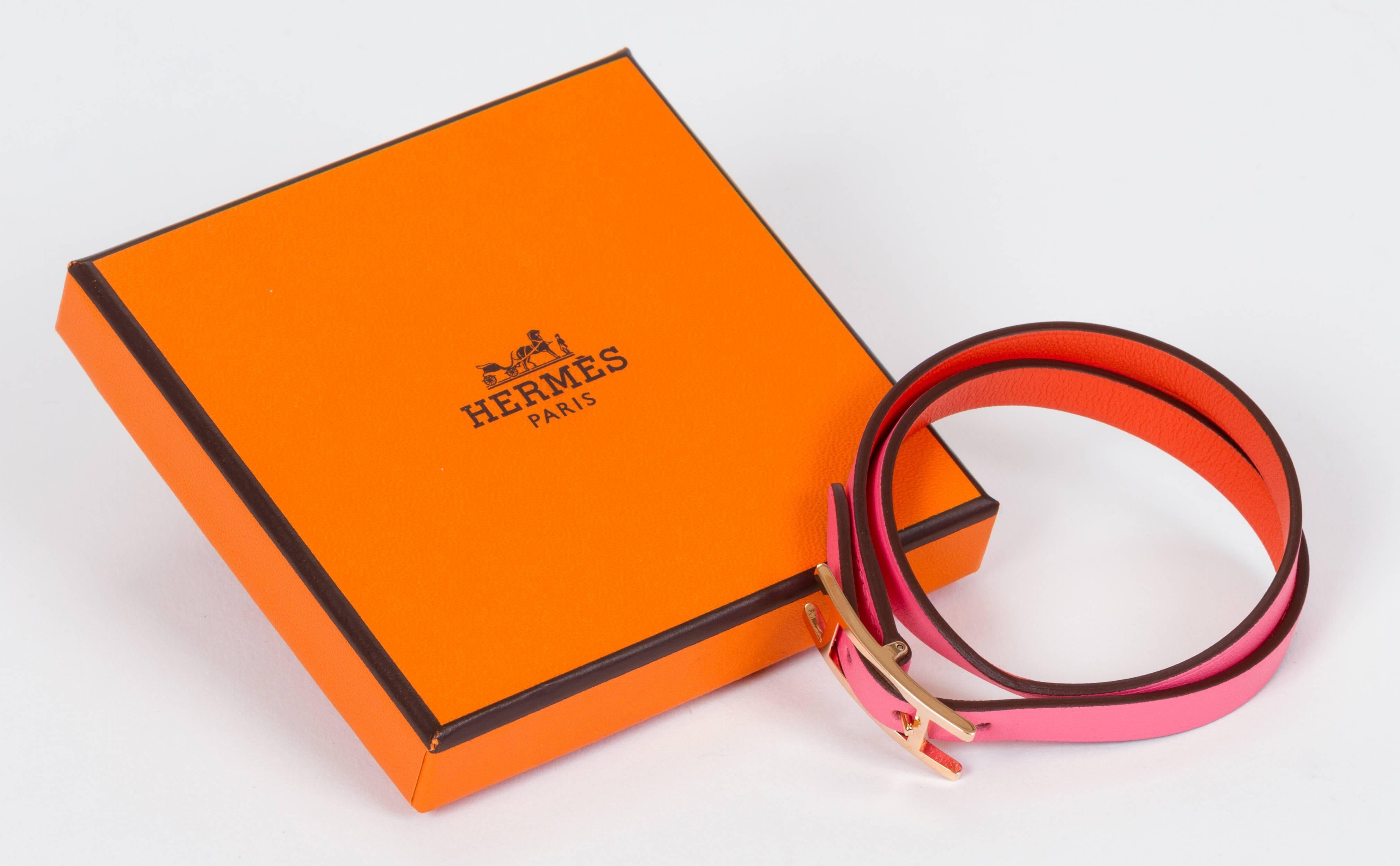 Hermès reversible rose azalee and orange poppy swift leather wrap bracelet. Rose gold buckle. Size M. Comes with original velvet pouch, box, ribbon, and gift bag.