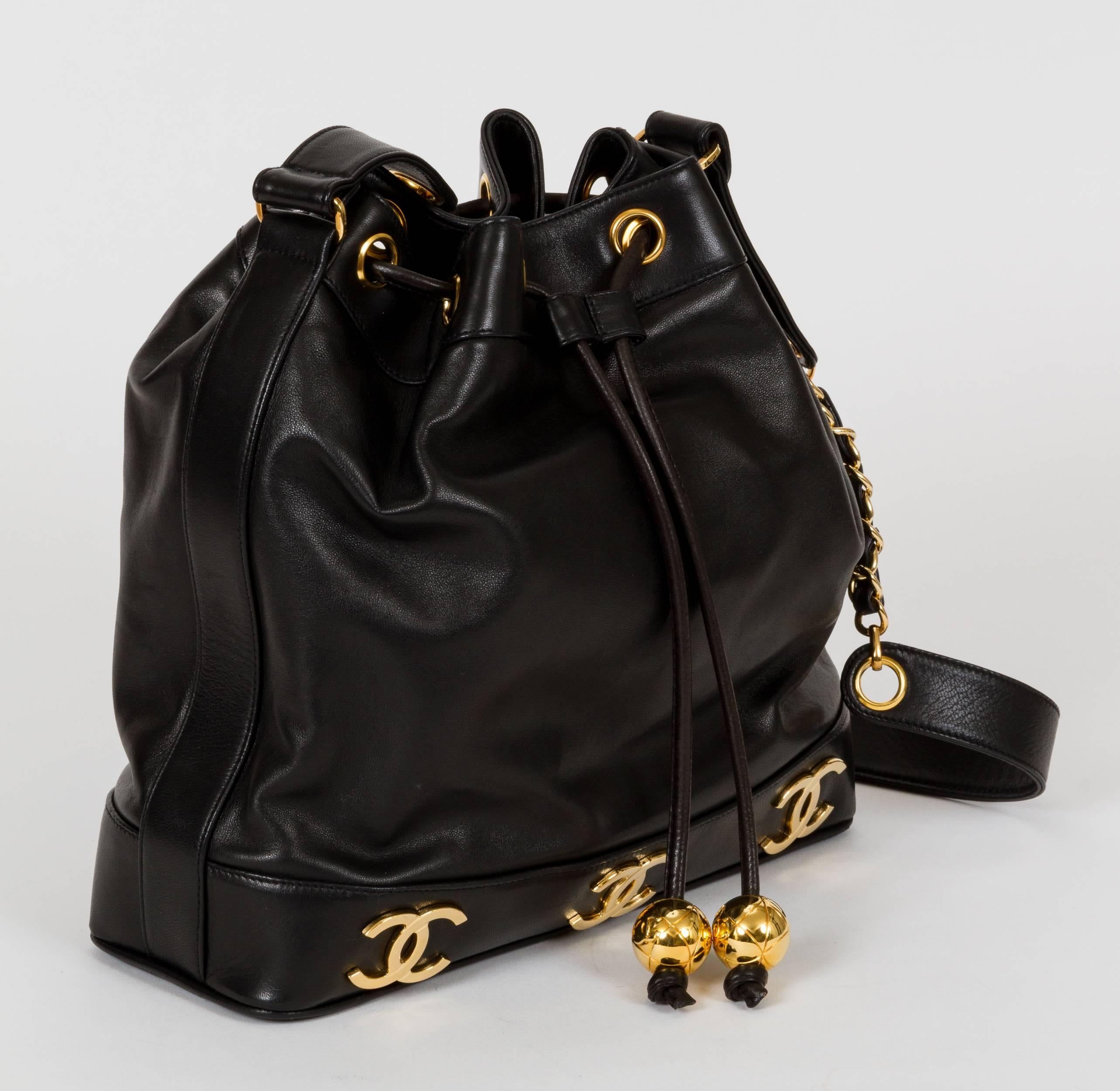 1990s Chanel black lambskin drawstring bucket bag with goldtone logo accents. Attached interior pouch. Shoulder strap, 19