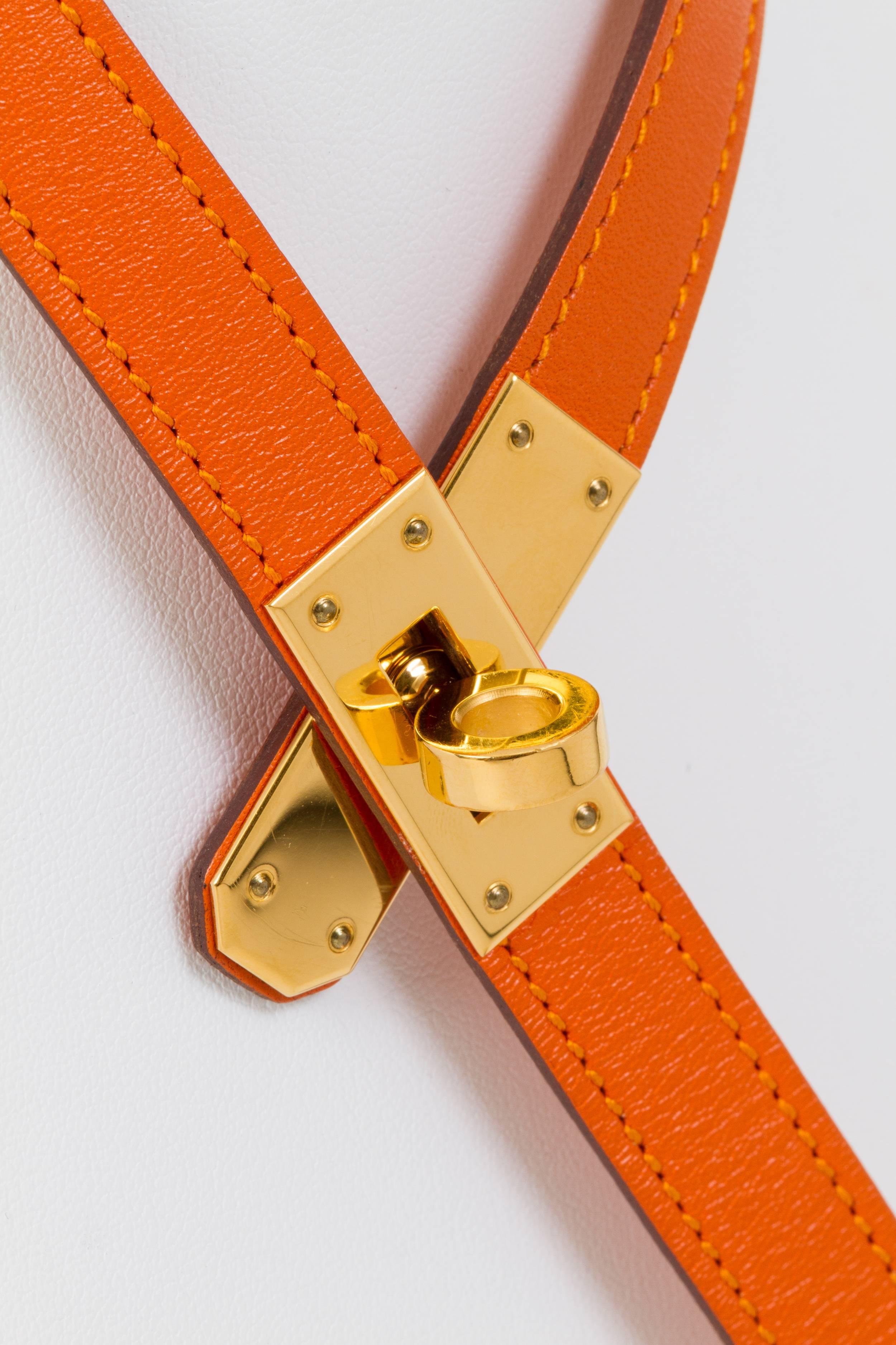 Hermès Kelly necklace in orange swift leather and goldtone hardware. Dated 