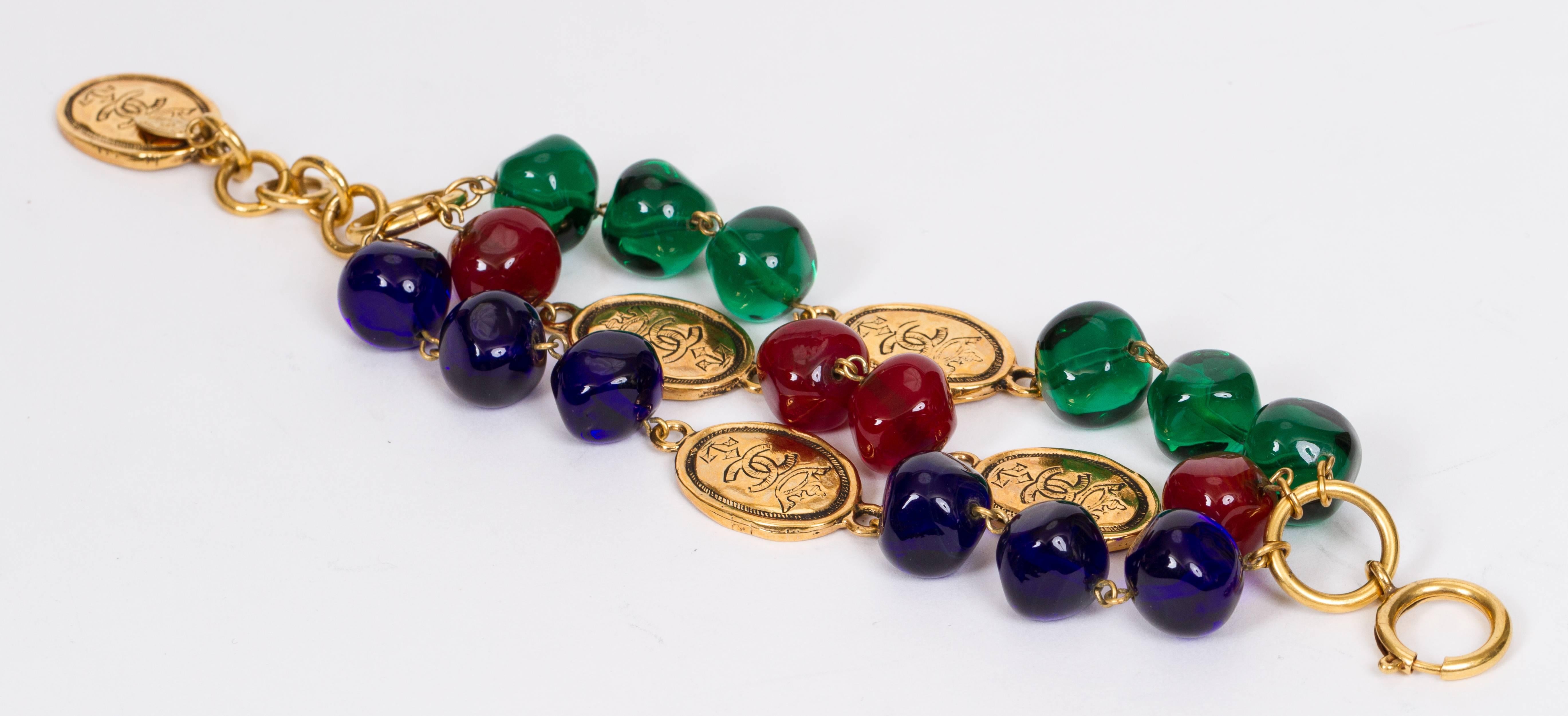 Chanel triple-strand red, blue, and green bead bracelet with goldtone logo coins. Collection 26 mid 1980s. Comes with velvet pouch.

