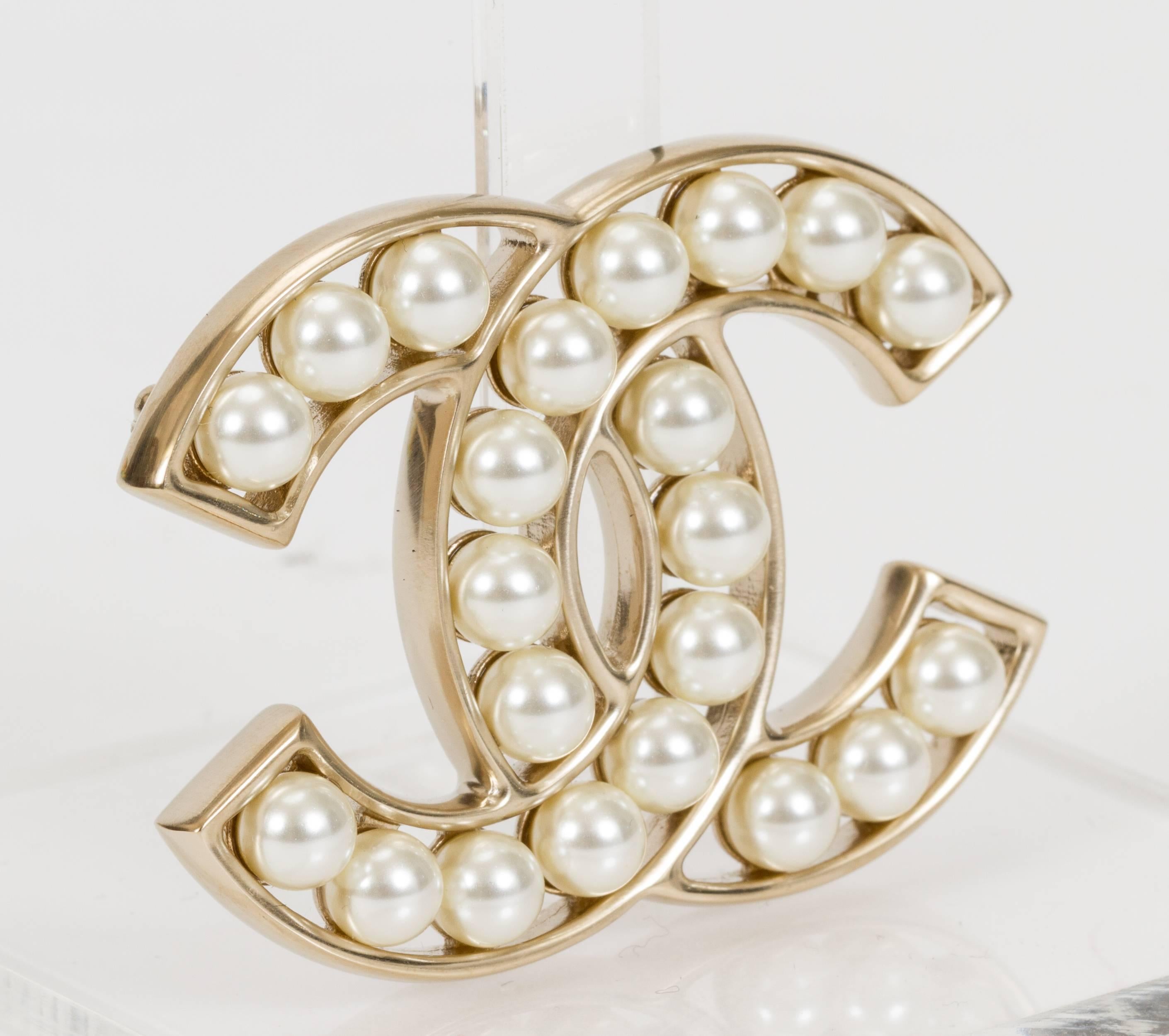 Chanel logo faux-pearl and silvertone brooch. 2015 collection. Comes with velvet pouch and box.