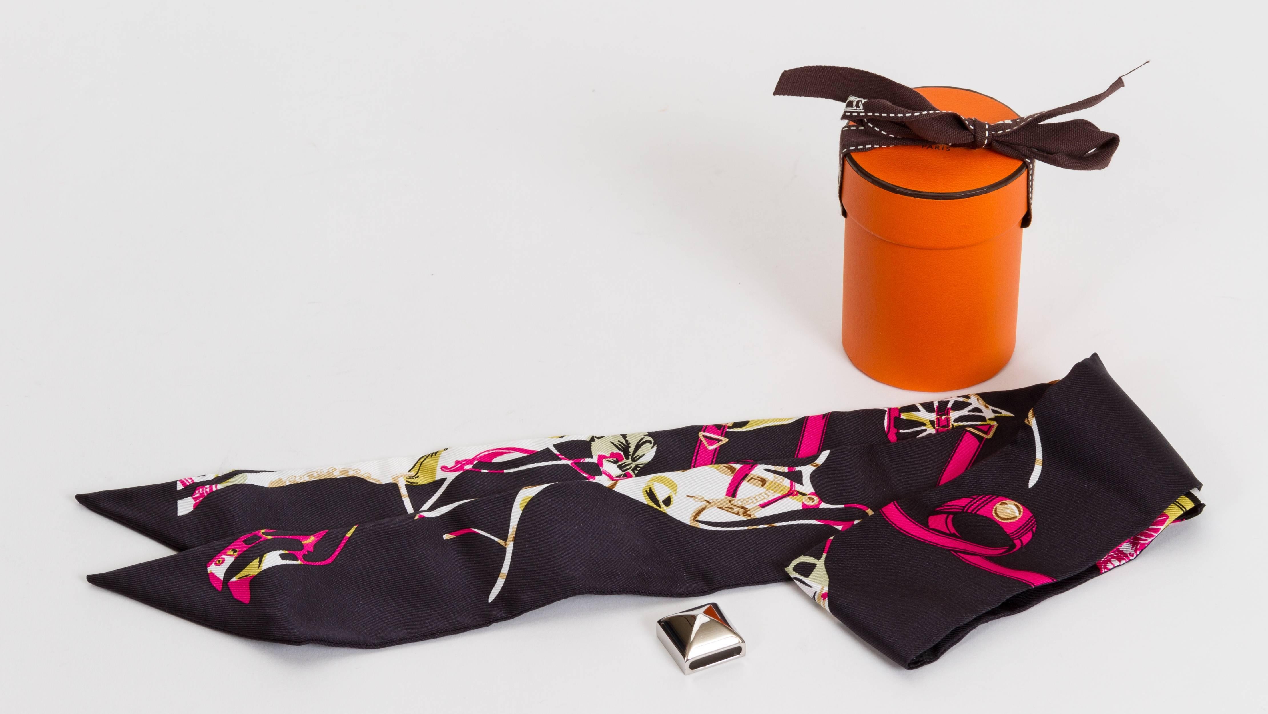 Hermès black 100% silk Twilly with pink carriage design with palladium medor metal slide. Can be worn as a bracelet or a scarf. Comes with original box and ribbon.