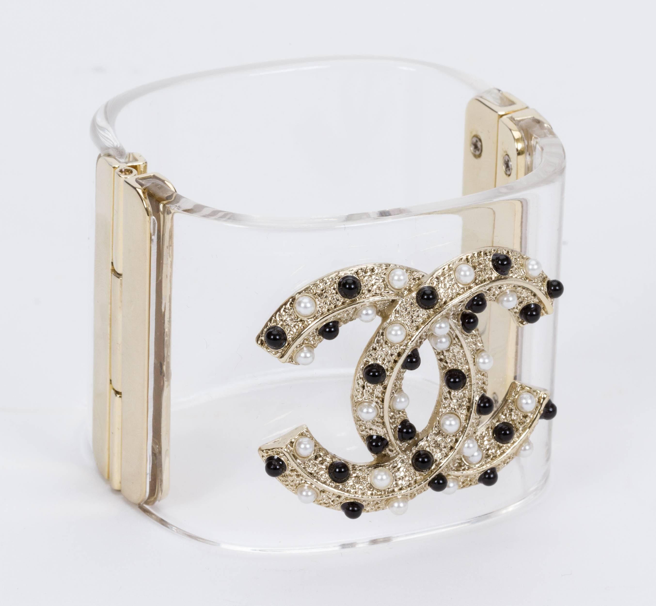 Chanel hinged contemporary lucite cuff. Front silver logo with gold and pearl beads. Collection autumn 2015. Comes with velvet original box.
