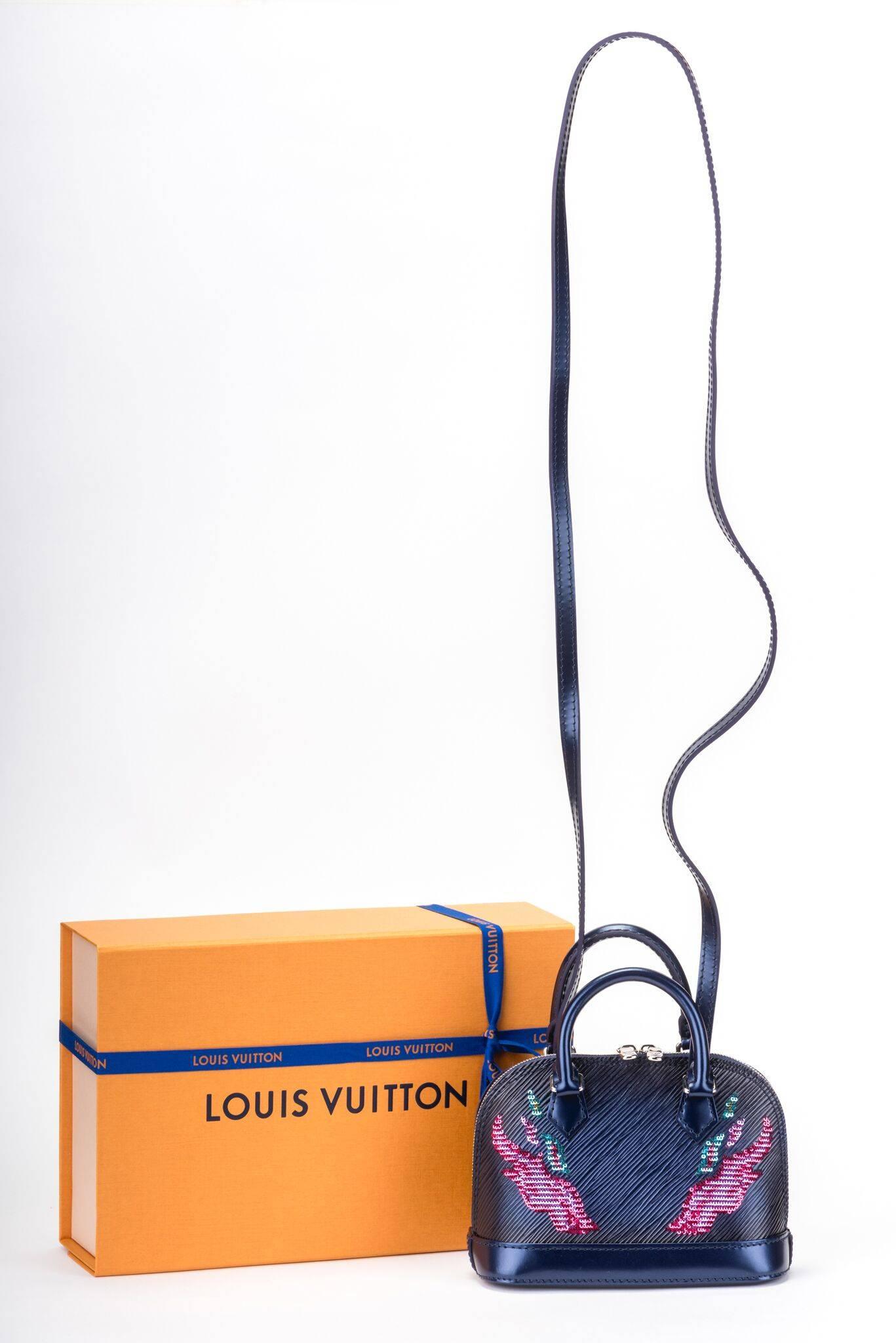 Louis Vuitton édition limitée nano alma en cuir épi avec design de flammes en paillettes. La sangle est détachable et la boîte est neuve, avec le ruban et la pochette.

Le sac mesure 6,5