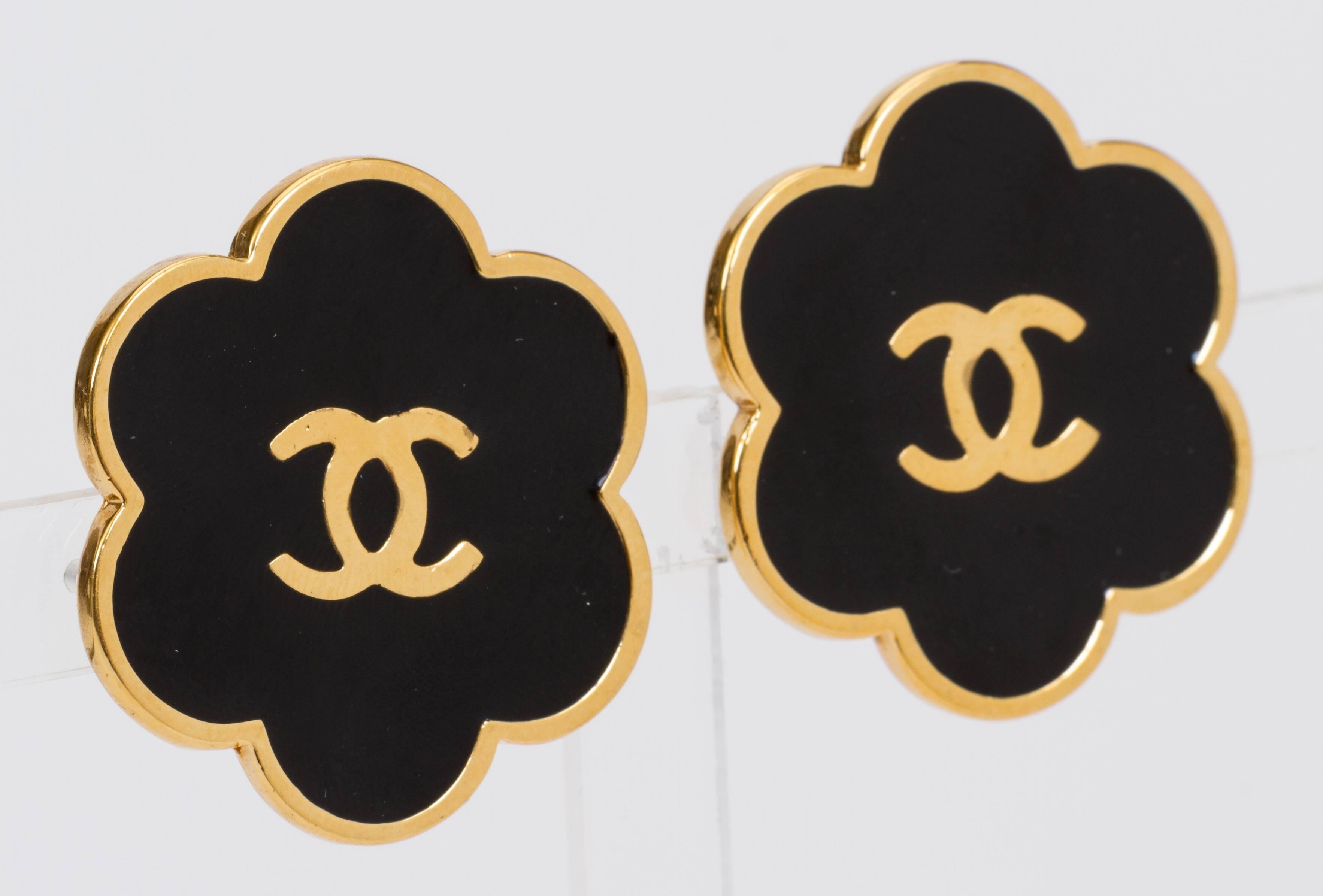 Chanel oversize black enamel and gold tone flower clip-back earrings with center logo. 1970s collection. Comes with original box.
