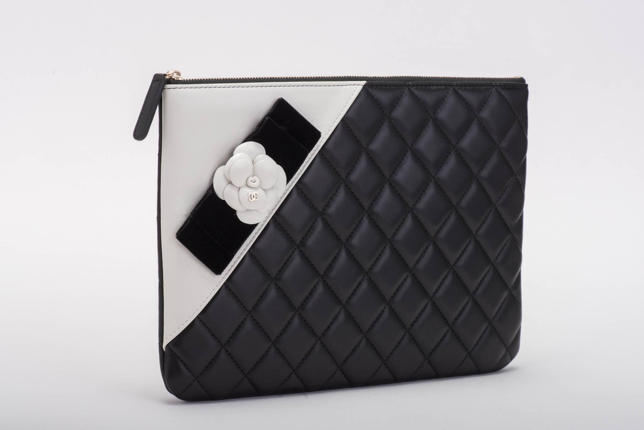 Chanel brand new in box timeless black and white quilted camellia clutch. Signature logo camellia with black velvet ribbon. Comes with hologram, ID card, booklet, box and ribbon.