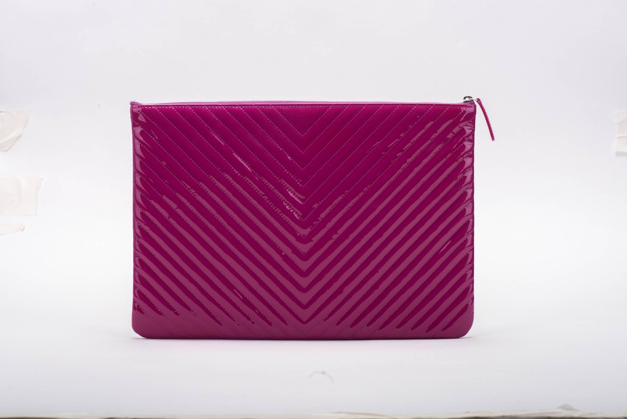 Chanel brand new in box chevron magenta patent leather quilted clutch. Signature CC center logo. Comes with hologram, ID card, booklet, box and ribbon.