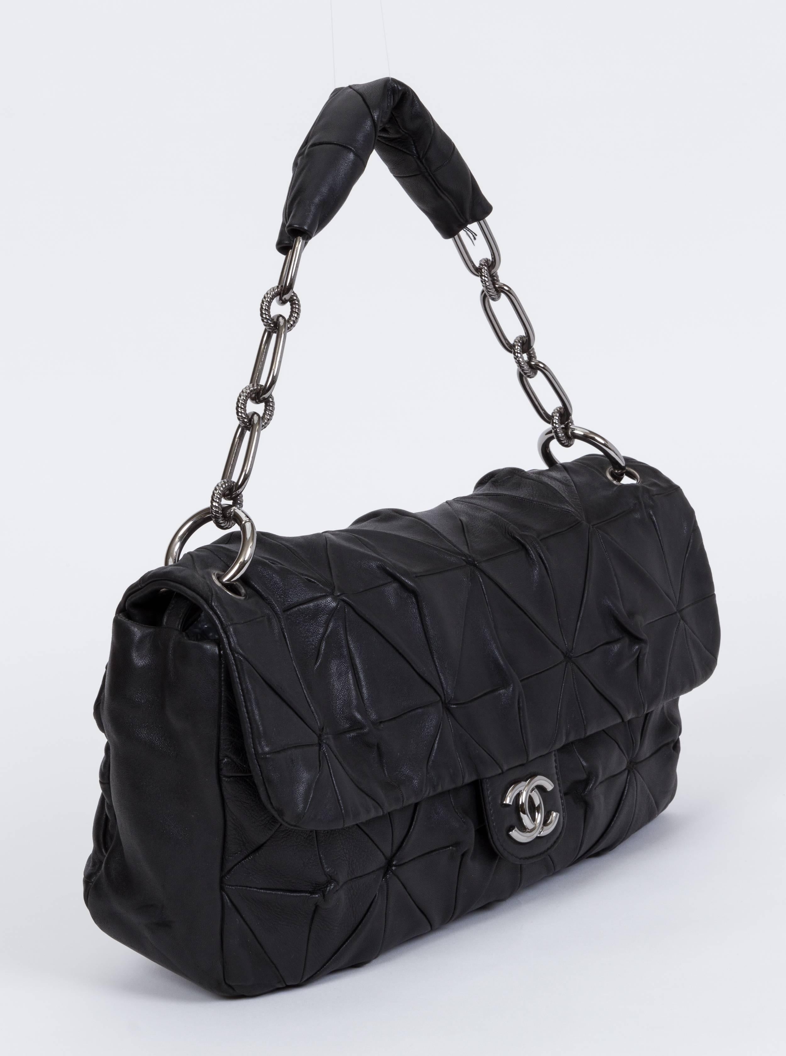 Chanel maxi single flap in black lambskin with silver tone hardware. Origami original quilting. Shoulder drop 8