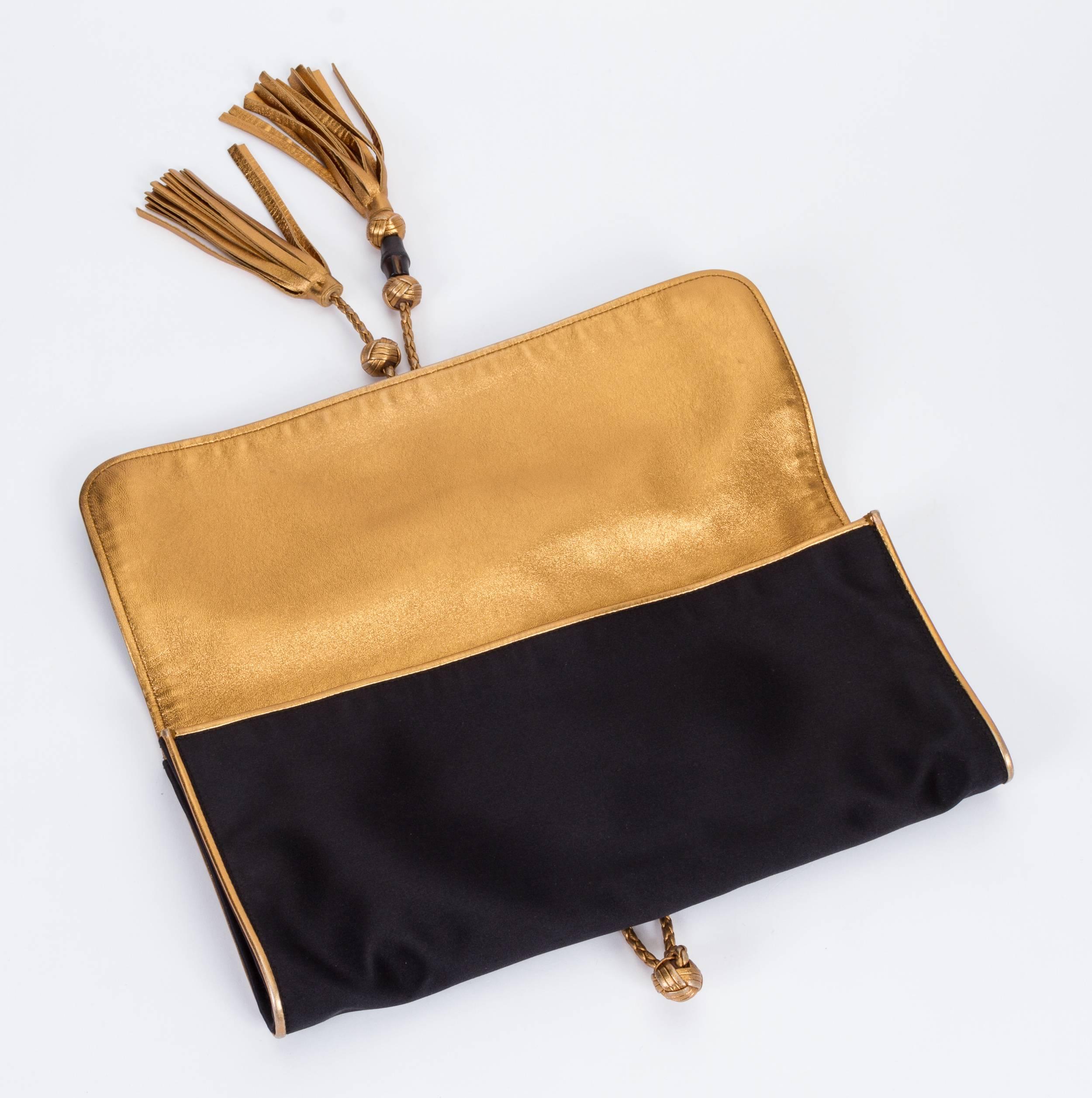 Gucci black silk satin and gold lambskin envelope oversized clutch with fringe tassels. Bamboo detail and Gucci metal logo slide. Excellent condition. Zipped interior . Comes with booklet and original dust cover.
