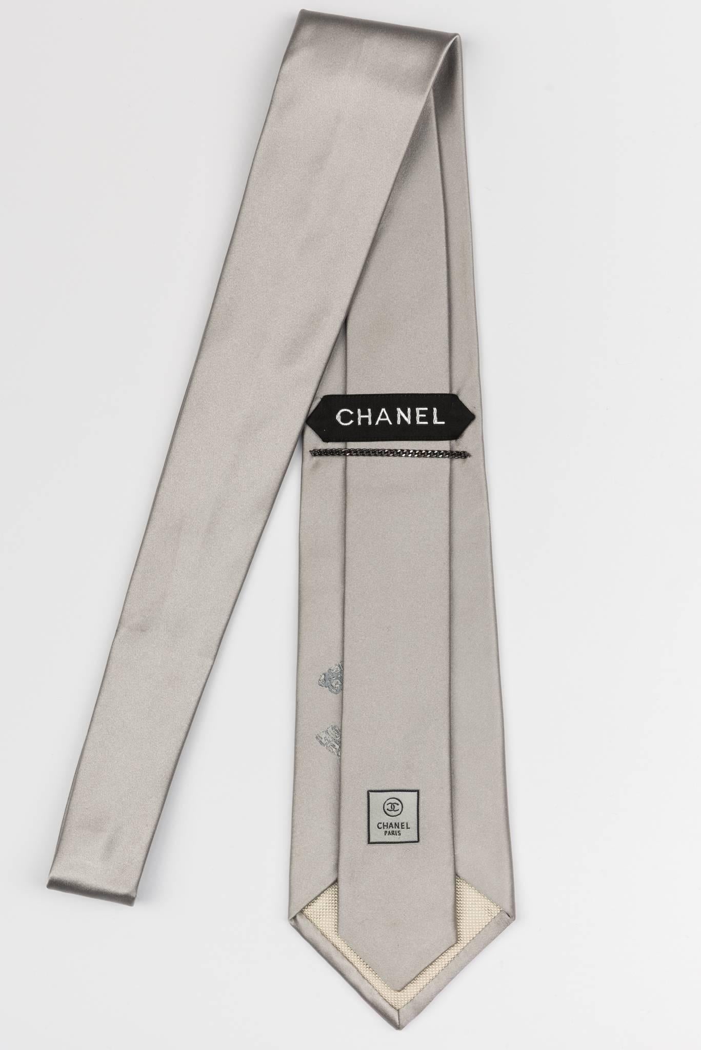 Chanel new in the original packaging and in excellent condition; Silver solid silk tie with oversize CC logo detail.