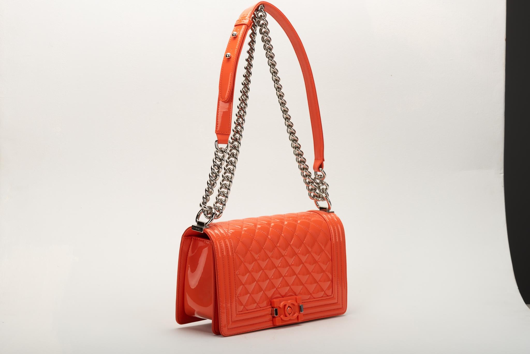 Chanel medium boy bag in orange patent leather , orange lambskin lining and silver tone hardware. Shoulder drop 11