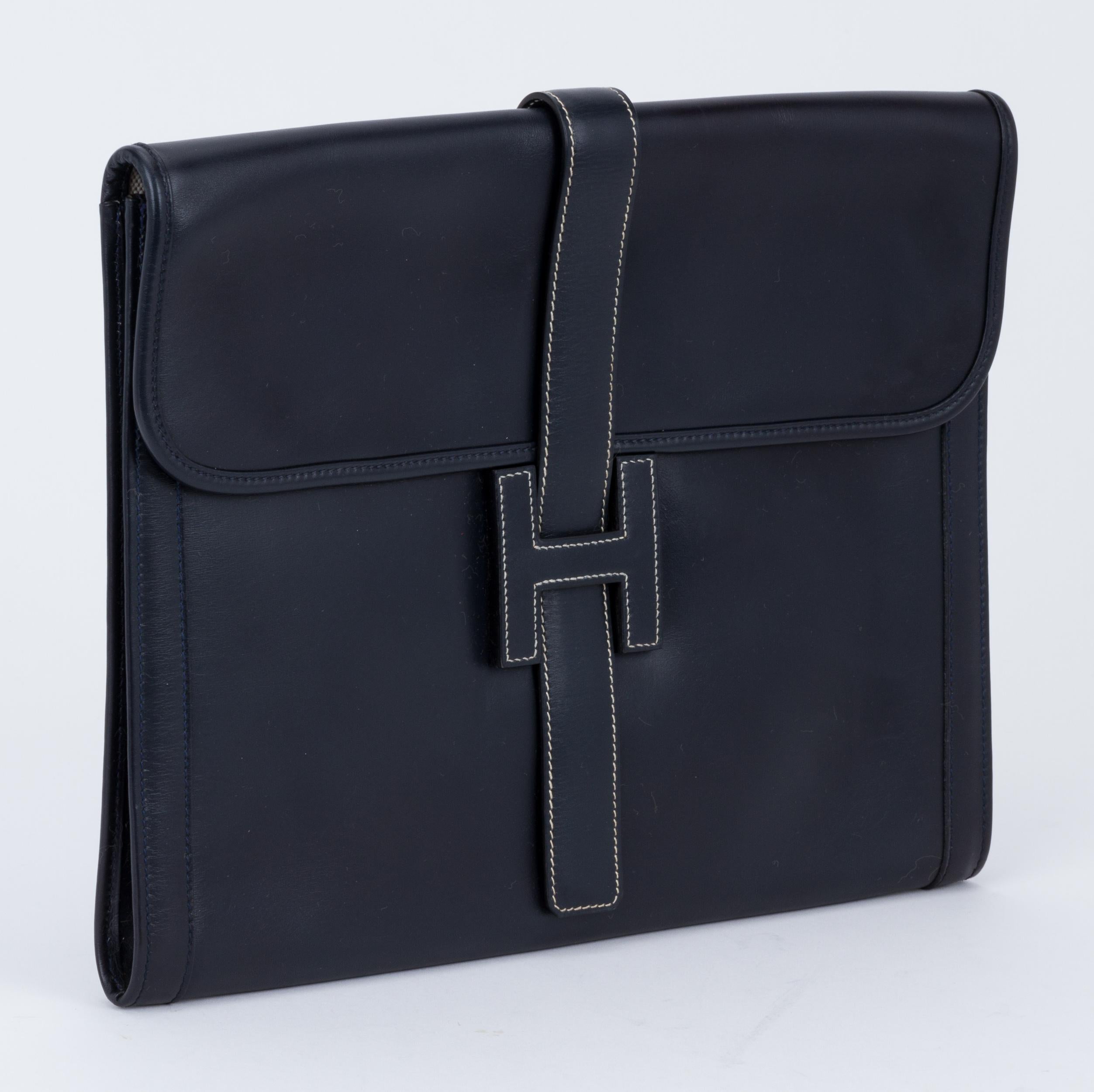 Hermès navy blue box calf leather oversize jige clutch. Contrast stitching and interior cream toile. Minor stains in the bottom interior. Minor scuffs on corners. Date stamp S for 1989. Comes with original duster.