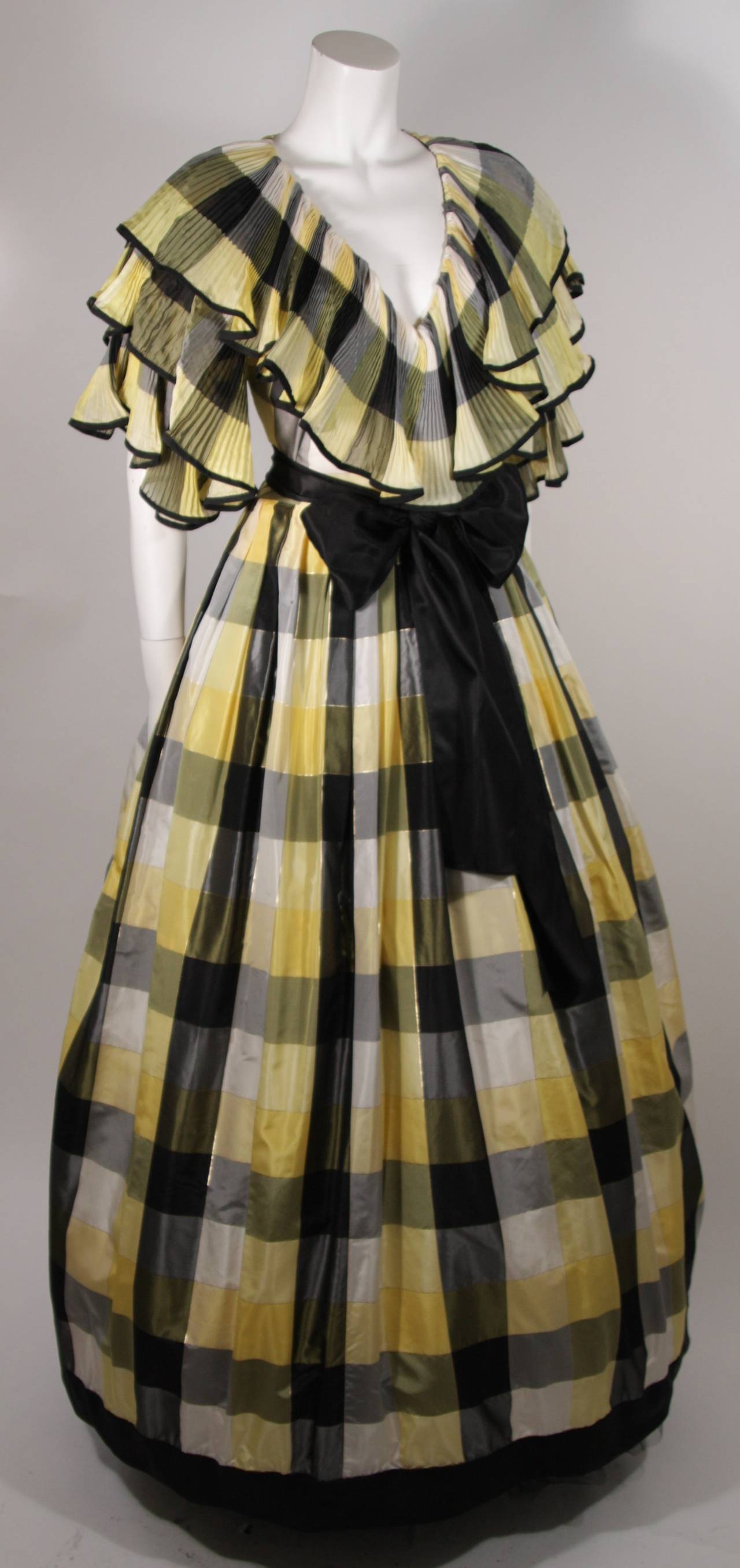 This Paul Louis Orrier gown is composed of a yellow and black plaid silk. The v-neckline is fabricated from pleated and ruffled layers of the patterned silk. There is a side zipper for ease of access. Made in France. Comes with black silk bow.