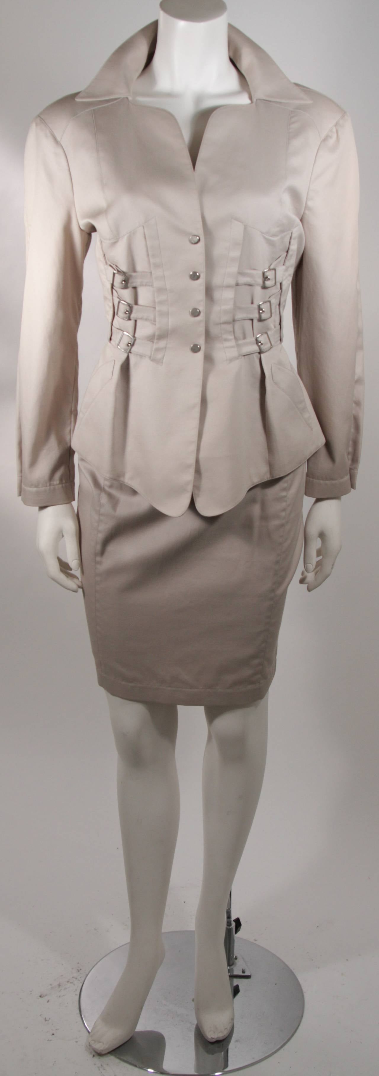 This Thierry Mugler skirt suit ensemble features a classic Thierry Mugler silhouette which embodies strength, power, and femininity. The jacket is accented with silver buckles and a slight peplum flare (Snap closures). The skirt is a classic pencil