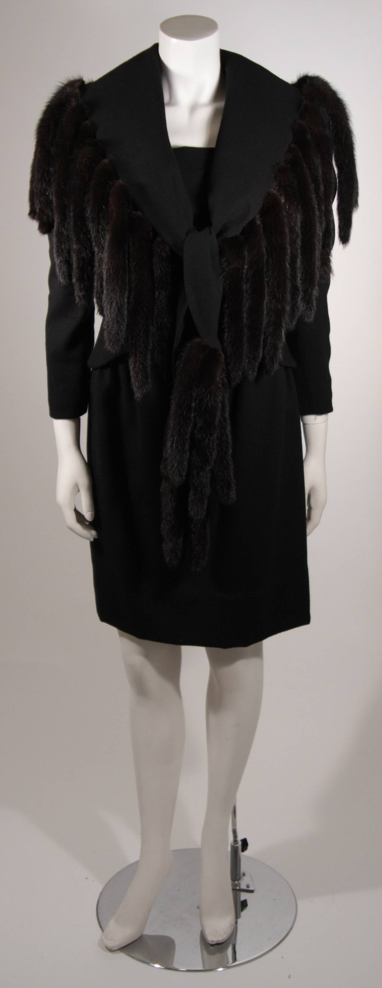 This Travilla design ensemble features two pieces. The wonderful jacket has a stunning mink trim and center front button closures. The dress is a classic style and features a center back zipper closure. Composed of a black non stretch wool.