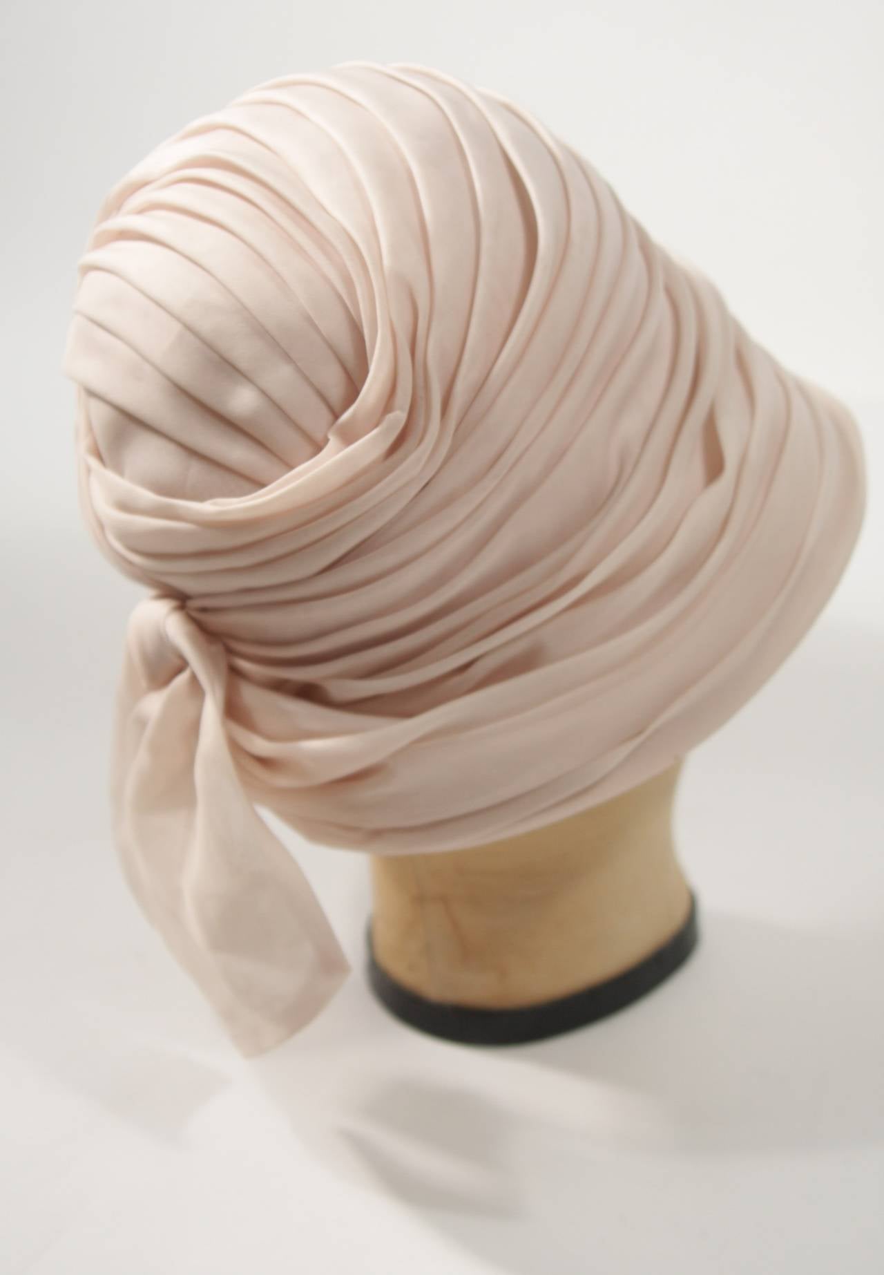 This Christian Dior hat is composed of a wonderful peach hued cream. Features a pleated and gathered design with a bow accent. Made in France. 

Measures (Approximately)
Circumference: 20