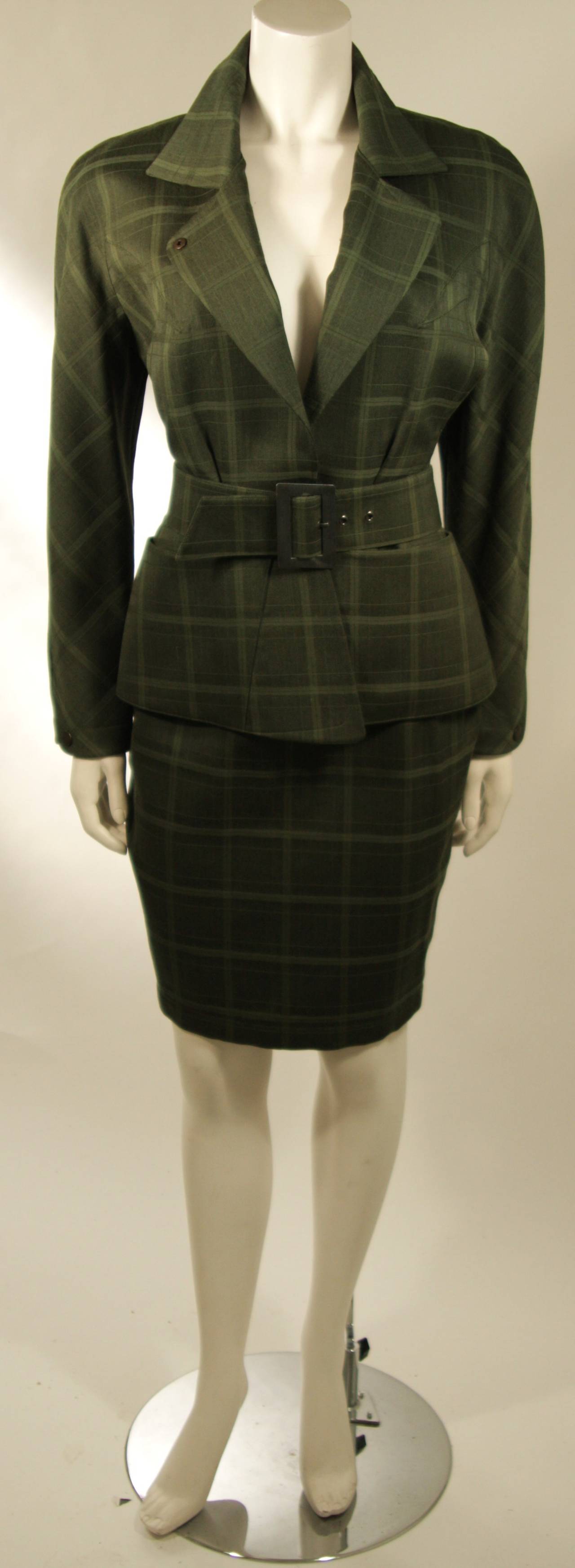 This Thierry Mugler ensemble is composed of green plaid. The suit features a classic Mugler silhouette which embodies strength, power, seduction, and sophistication. The jacket is cut to skim the female form with perfection, there are front pockets