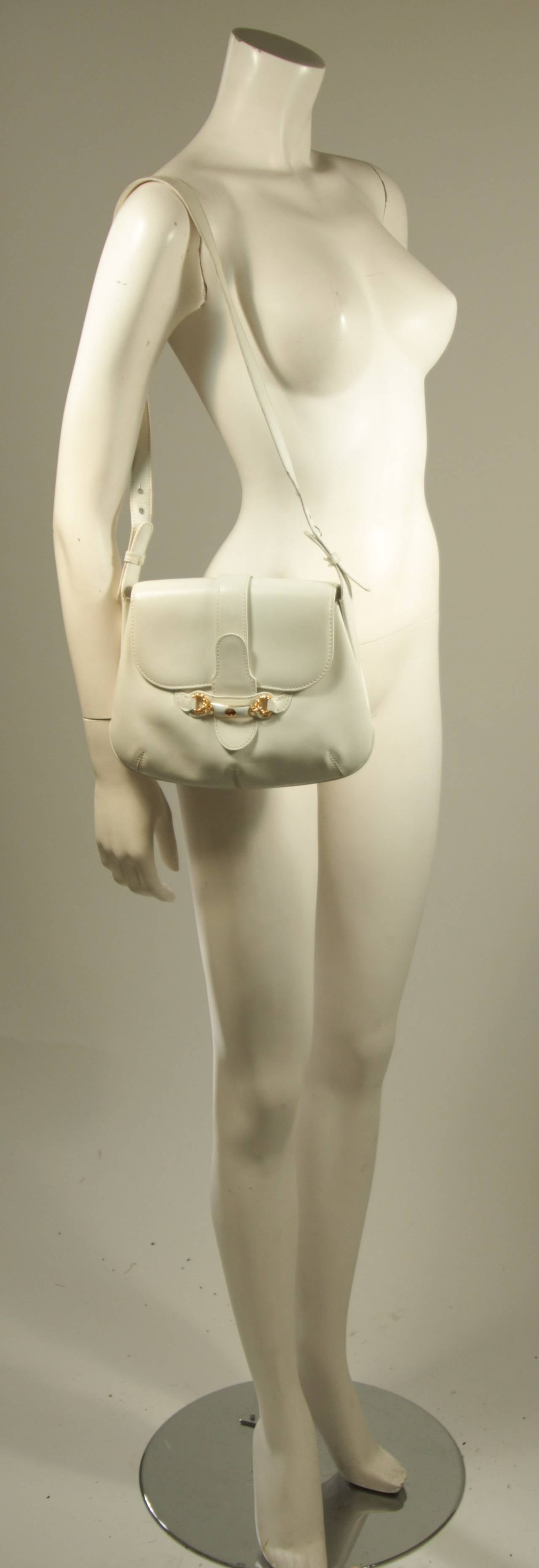 This Gucci purse is available for viewing at our Beverly Hills Boutique. The purse is composed of a white leather (the bag shows slight signs of wear and marks). The closure features the classic Gucci horse bit design. There are two interior