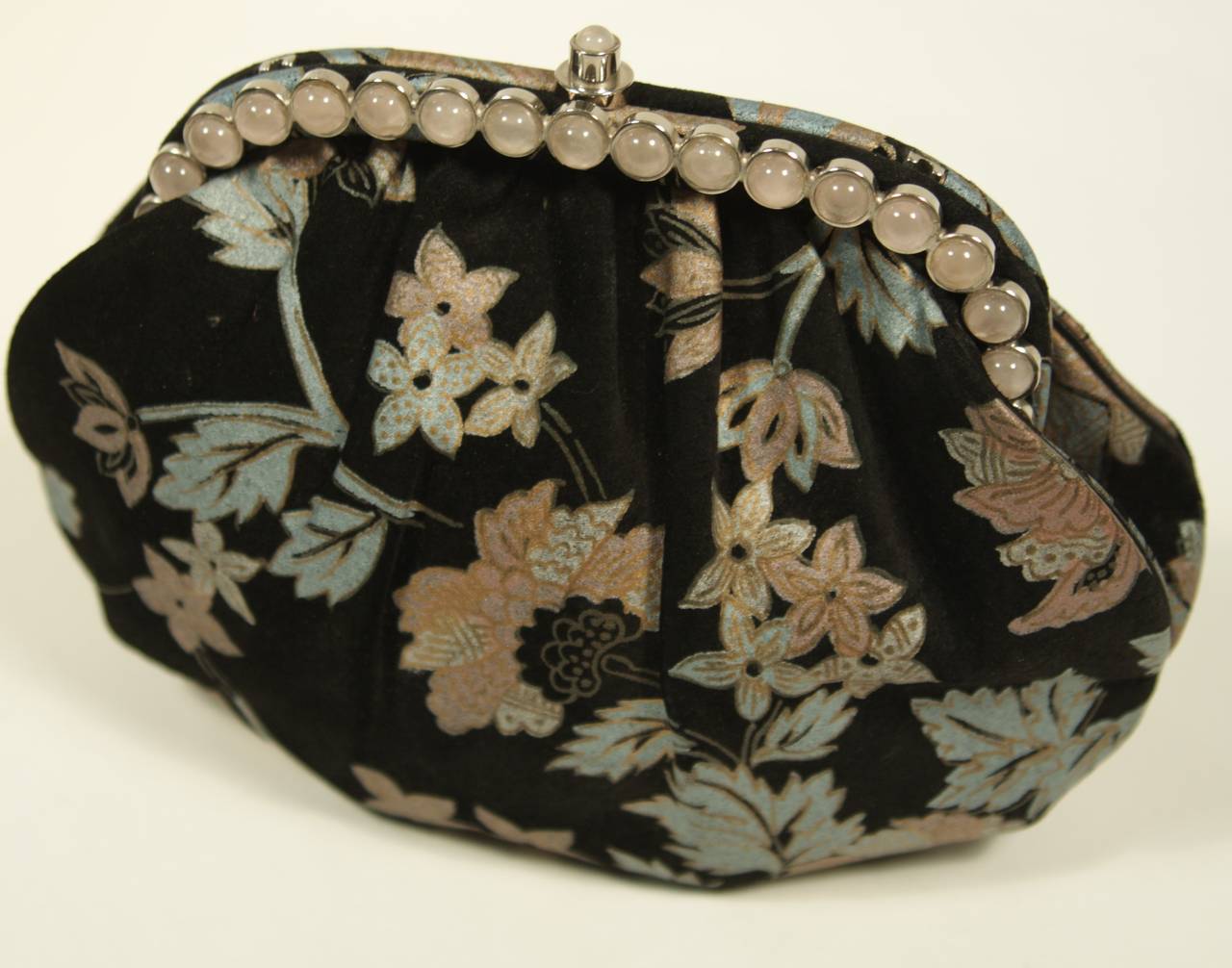 This wonderful Judith Leiber design is available for viewing at our Beverly Hills Boutique. The bag is fashioned from a black suede featuring a printed floral motif and accented by lovely pink stones. The interior is silk lined and in excellent