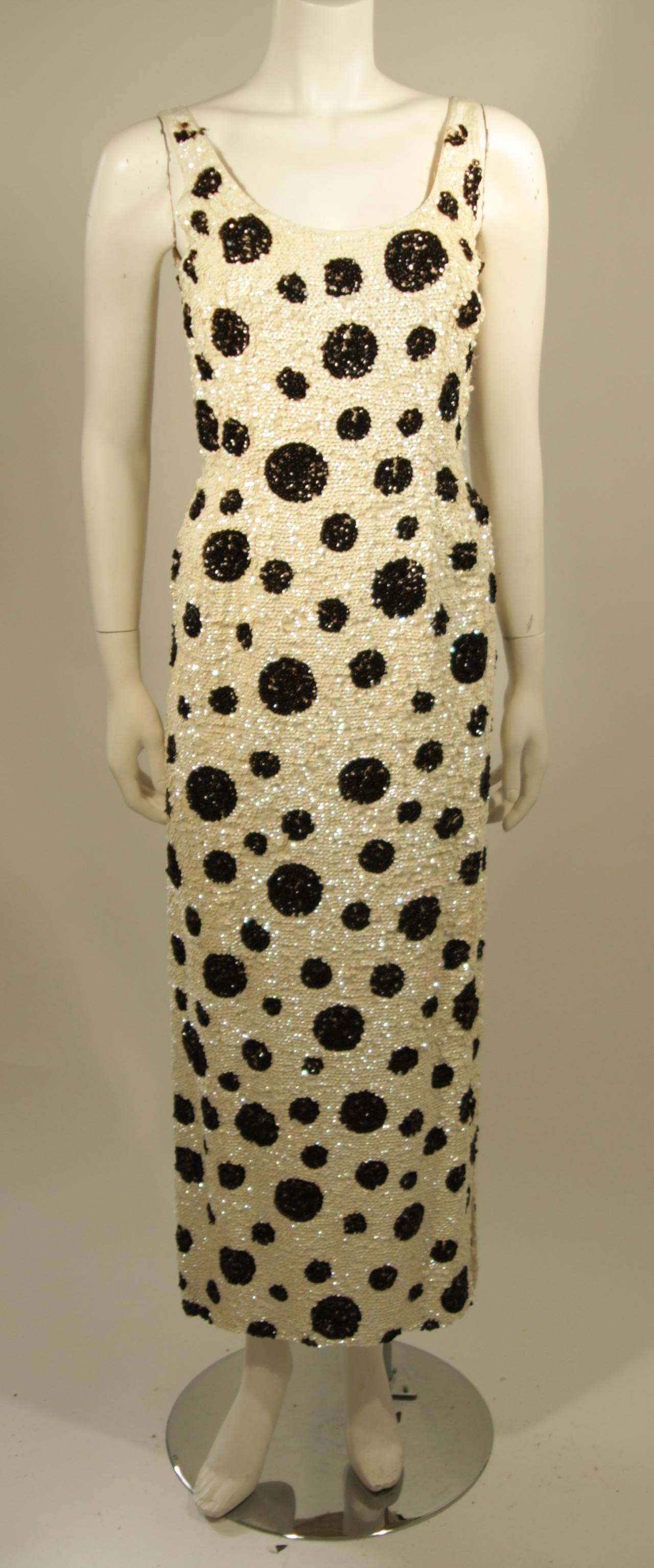 This sequin gown is composed of white and black sequins in a polka dot pattern. There is a zipper back closure. The shoulders are worn and missing sequins (we offer alterations and repairs/restoration, we all have a large stock of sequined