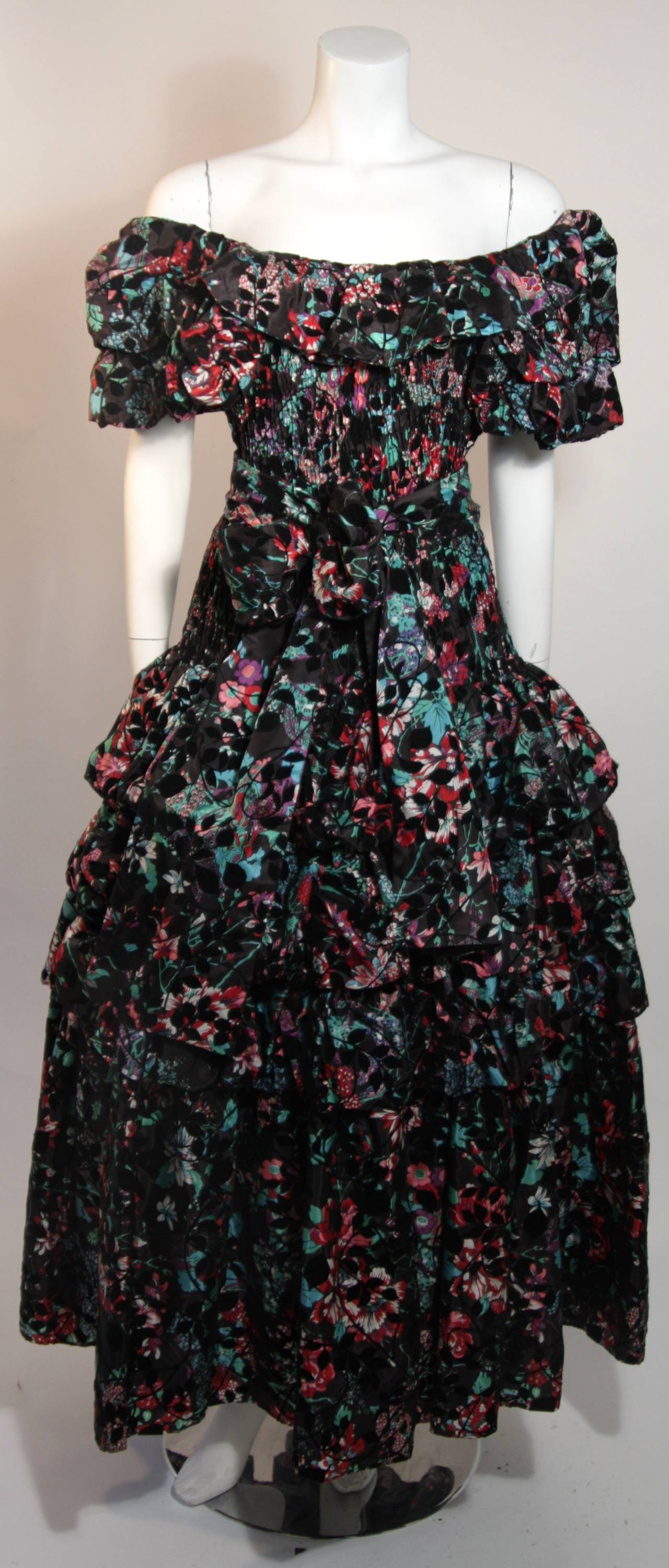 This wonderful Diane Fres design is available for viewing at our Beverly Hills Boutique. The gown is composed of a vibrant textile featuring velvet accents. The smocked bodice is accentuated by a ruffled and tiered skirt. The dress is pull on style