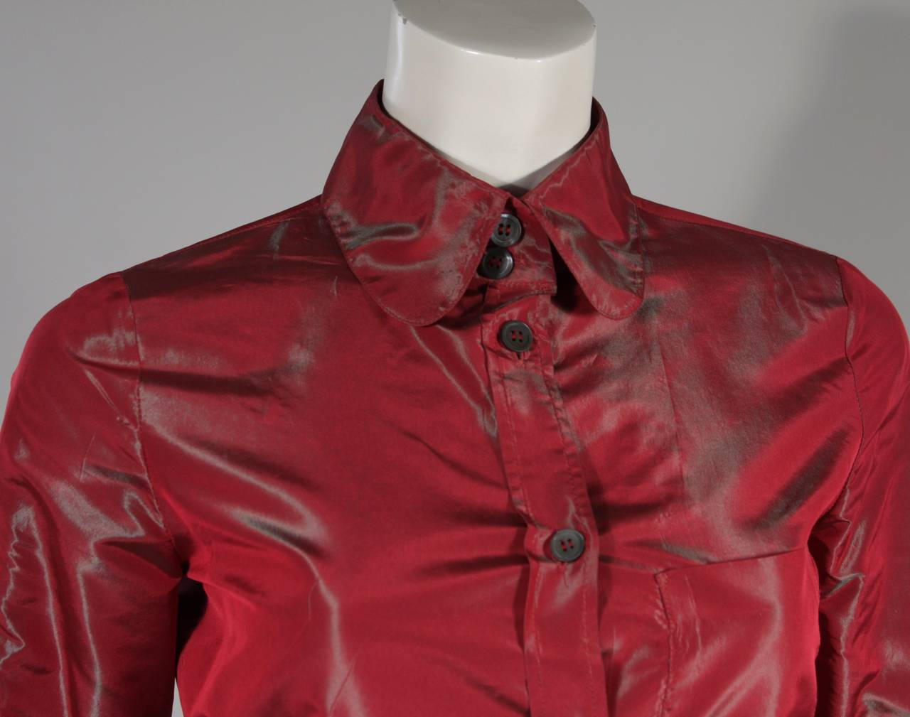 This Romeo Gigli blouse is composed of an red-iridescent fabric with center front button closures. Made in Italy. 

Measures (Approximately)
Length: 26.5