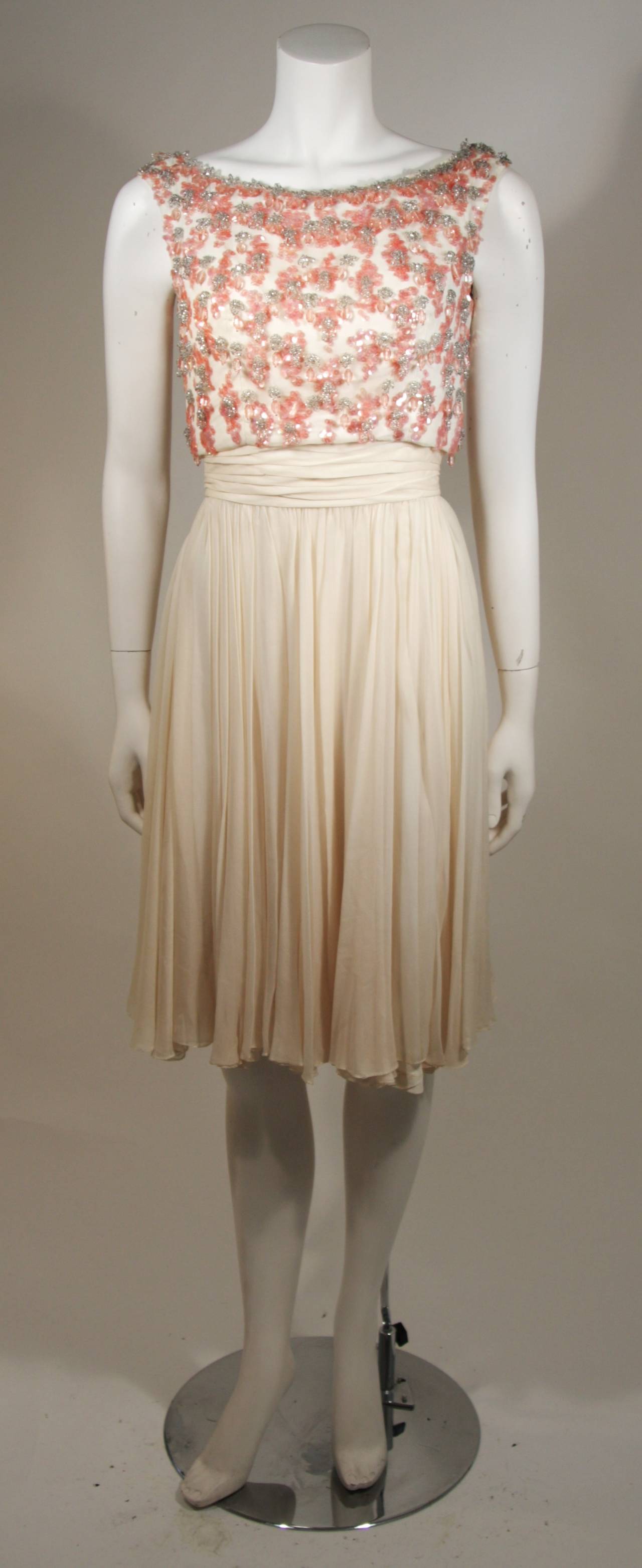 This Pat Sandler for Highlight cocktail dress is composed of an ivory silk chiffon and features pink crystal accents on the bodice. There is a center back zipper. 

Measures (Approximately)
Length: 36