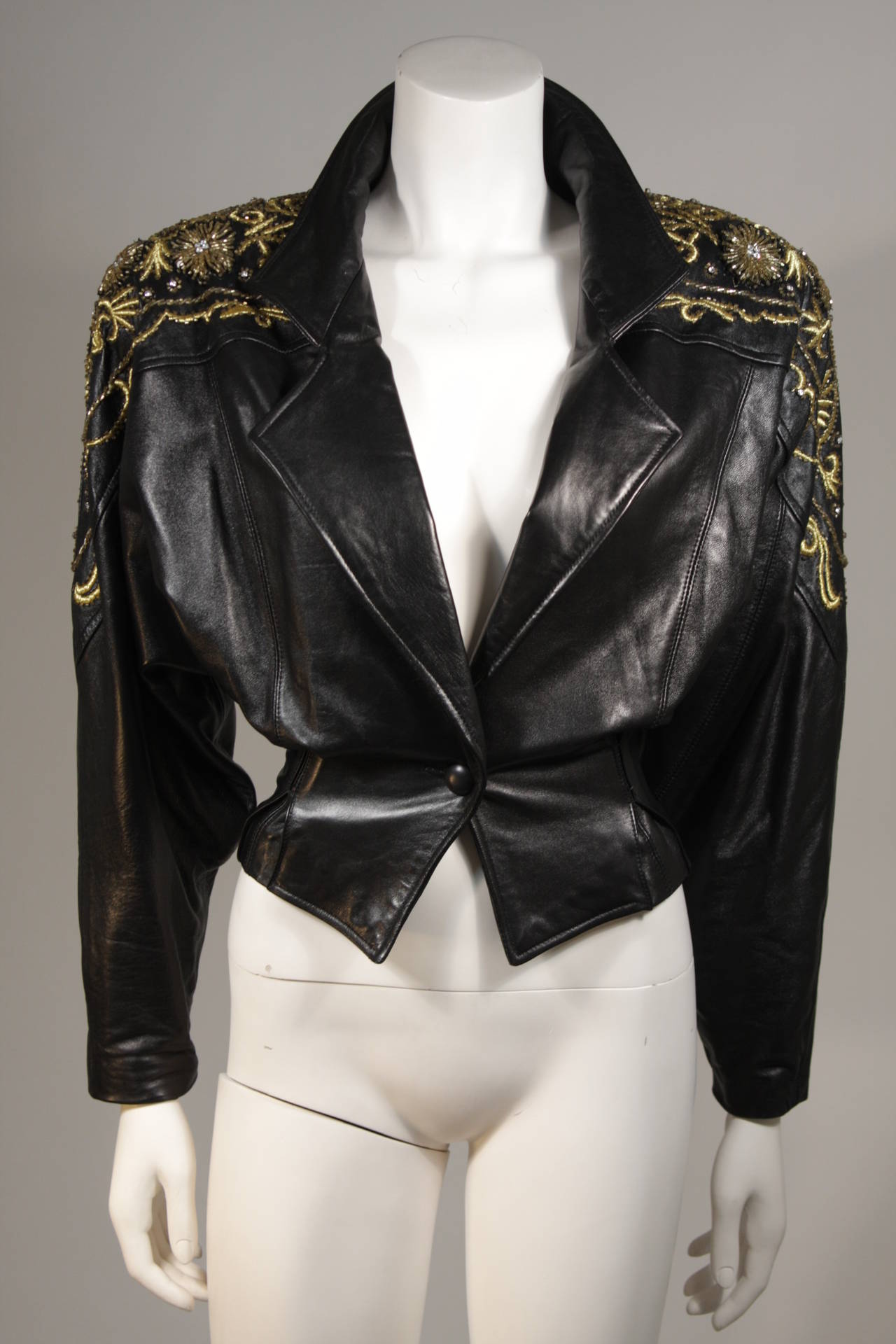 This Erez design is available for viewing at our Beverly Hills Boutique. The jacket is a composed of a supple black leather with gold embroidery and beading. There is a center front button closure. The jacket comes with shoulder pads. 

Please