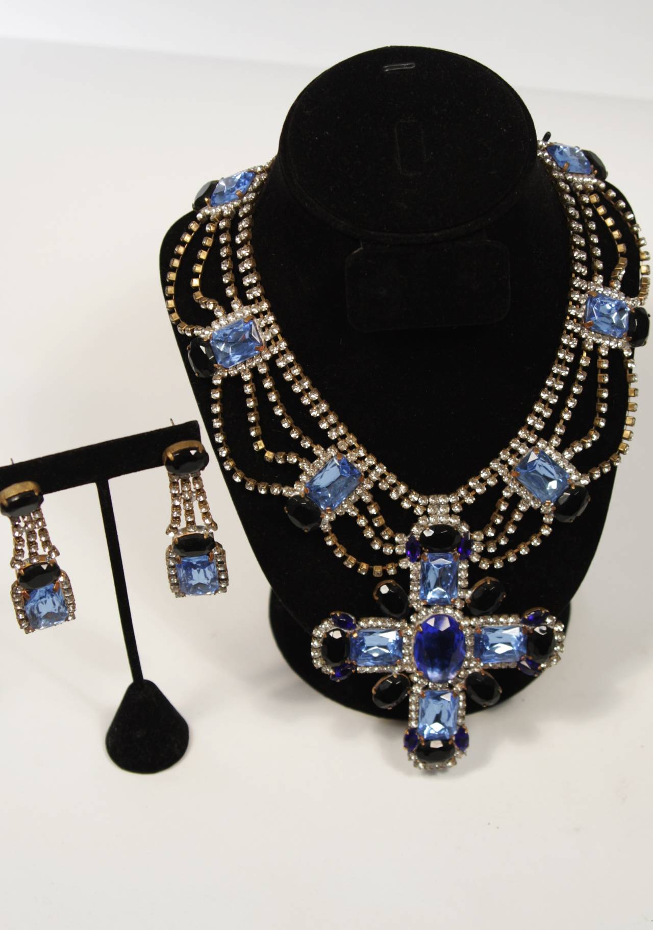 An exceptional necklace and earring set from Bijoux M.G., Czechoslovakia
Pale blue to dark blue sapphire rhinestones adorn the center cross design, with strands of white rhinestones around the pale blue gems around the neck. 

Measurements:
14