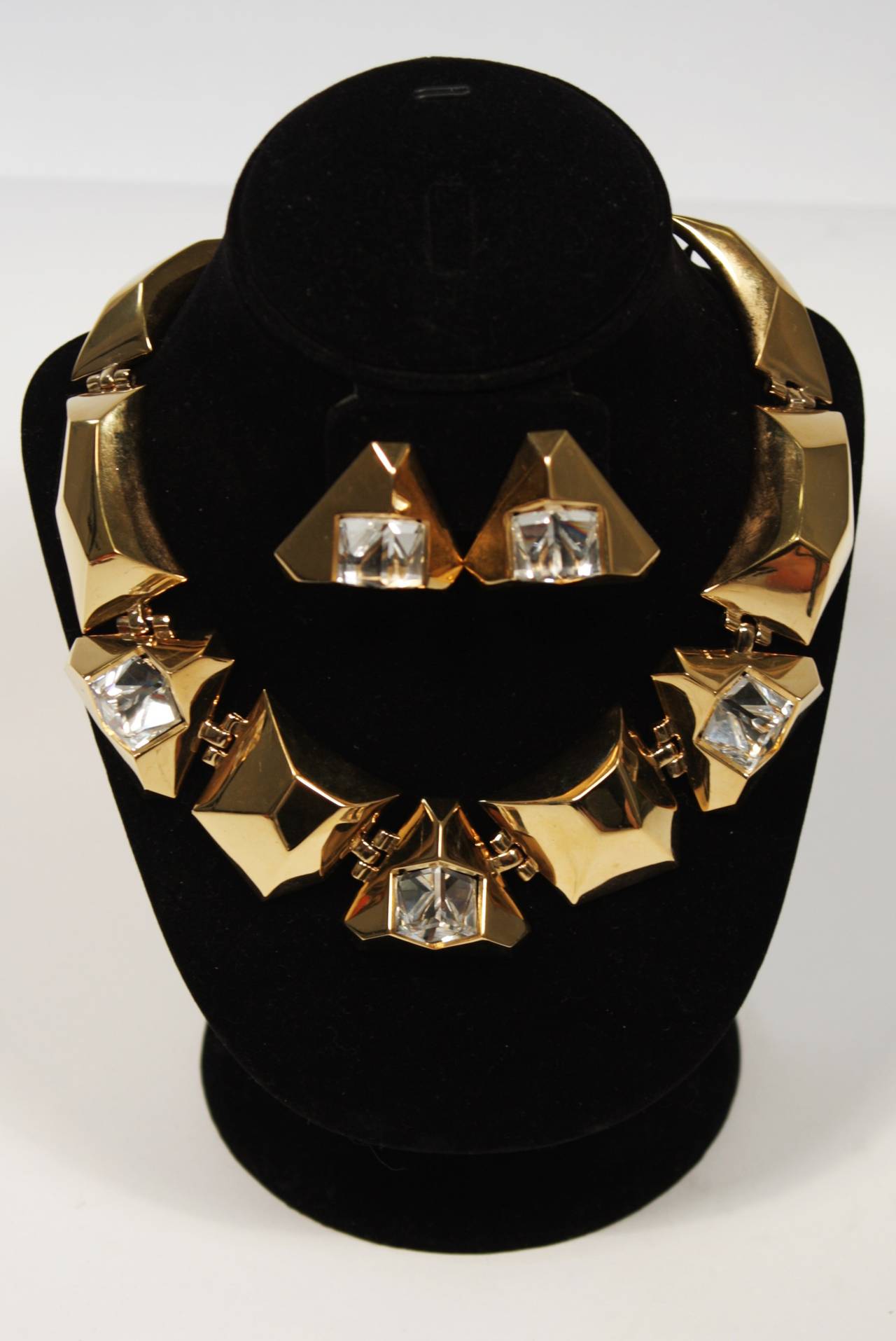 This Givenchy set is available for viewing at our Beverly Hills Boutique. The set is composed of a gold tone material and includes a necklace and earrings. They are set with a large clear rhinestone. 

Please feel free to contact us with any
