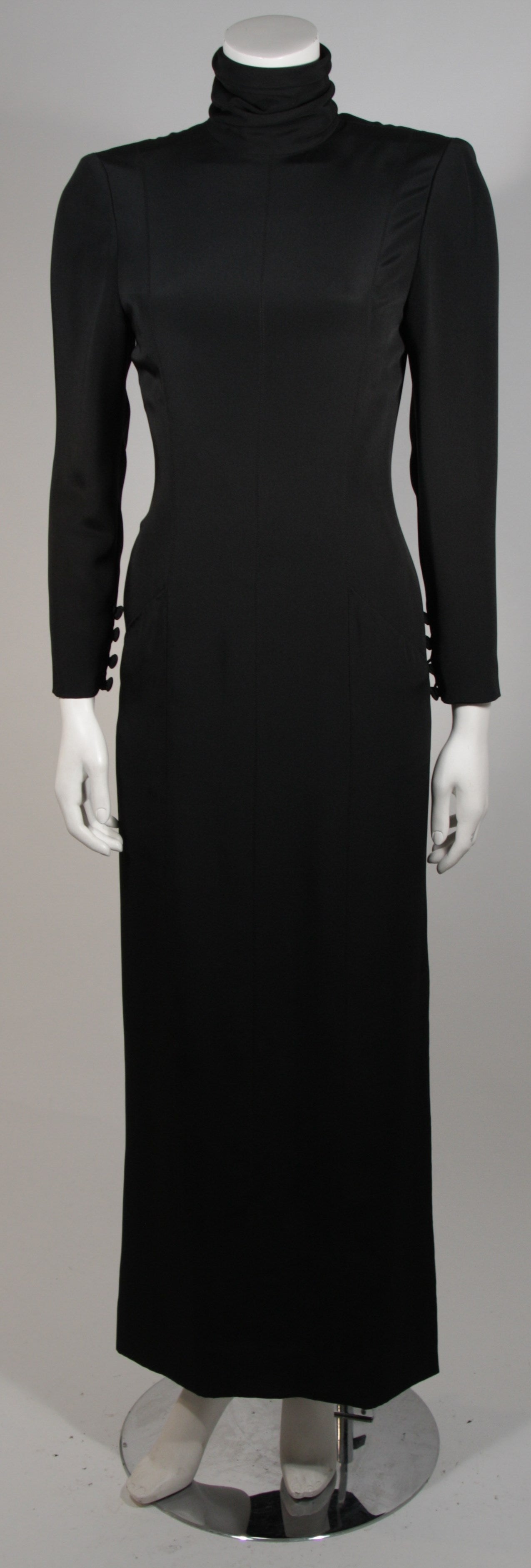 This Chanel gown is available for viewing at our Beverly Hills Boutique. The gown is composed of a black silk and features long sleeves with a high neck and gold button accents. There is center back zipper for ease of access. The piece is numbered.