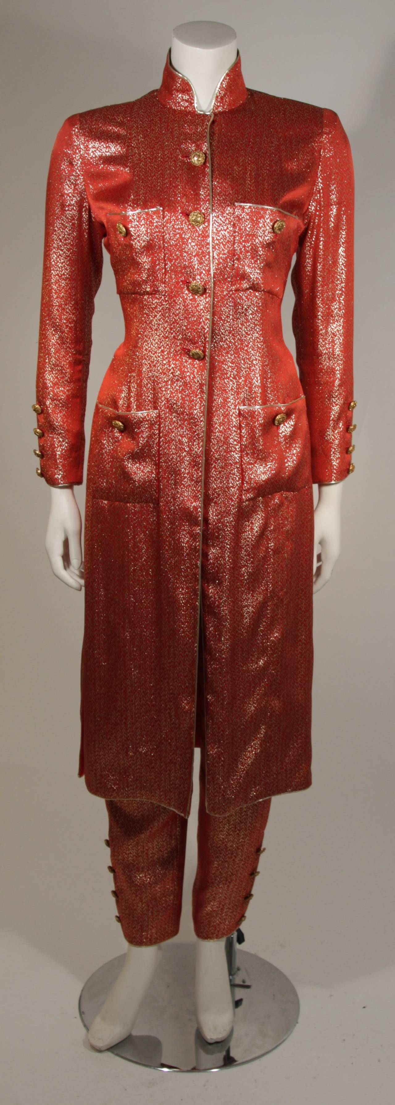 This Chanel suit is available for viewing at our Beverly Hills Boutique. The suit is composed of a silk lamé in an orange and gold variation and lined with a rich coral hued silk. The jacket features center front buttons, four front pockets, and a