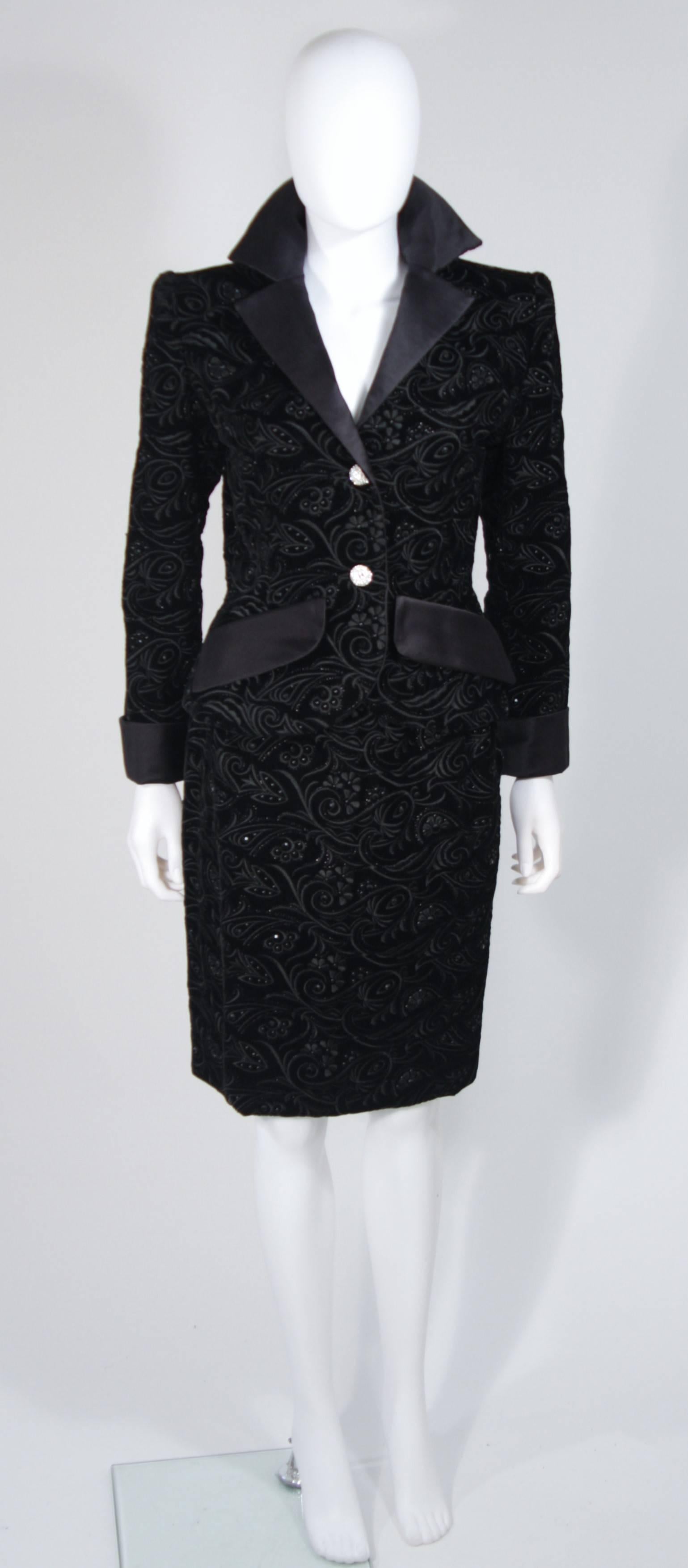  This Givenchy evening suit is composed of a black velvet, which is embroidered with a floral motif and adorned with rhinestones. The jacket features faux front pockets, center front rhinestone button closures, and silk trim. The skirt has a classic