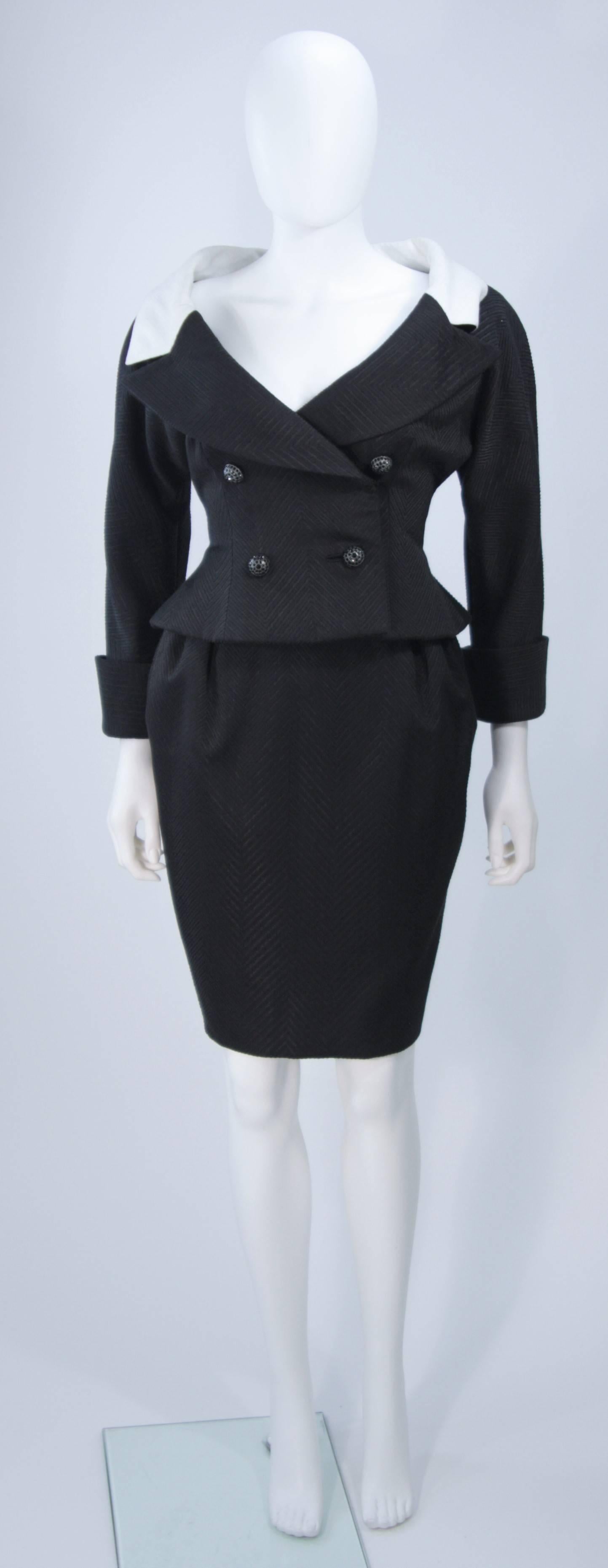  This Jean Patou Couture skirt suit is composed of a black and white contrasting linen combination. The jacket features a wide neck style with large black rhinestone buttons, a slight peplum flair at the waist, and center back bow detail. The skirt