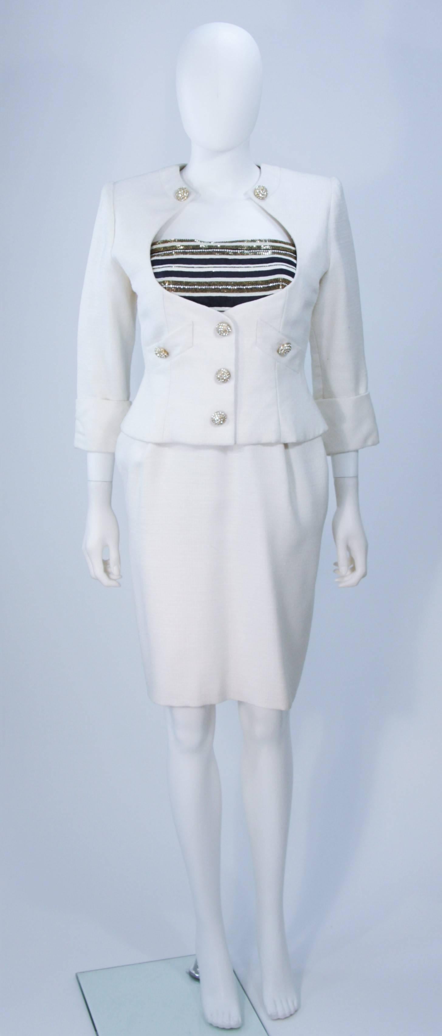  This Jean Patou Couture dress ensemble is composed of a beautiful white textured linen which is accented with rhinestones and beading. The jacket features an open style bust with gold rhinestone button closures and front pockets. The lovely