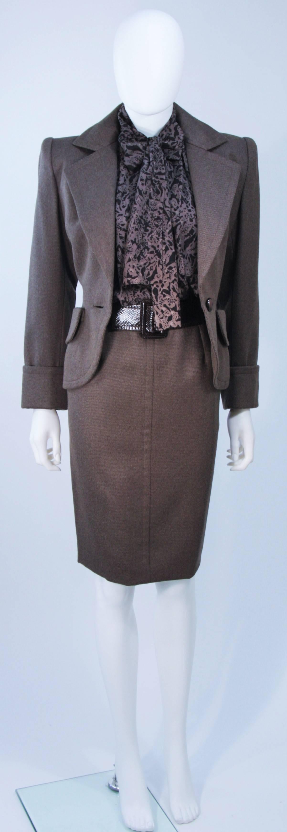  This Givenchy Couture skirt suit is composed of brown wool, a printed silk blouse, and a snakeskin belt. The jacket has center front button closures, structured shoulders, and front pockets. The printed silk blouse features center front button