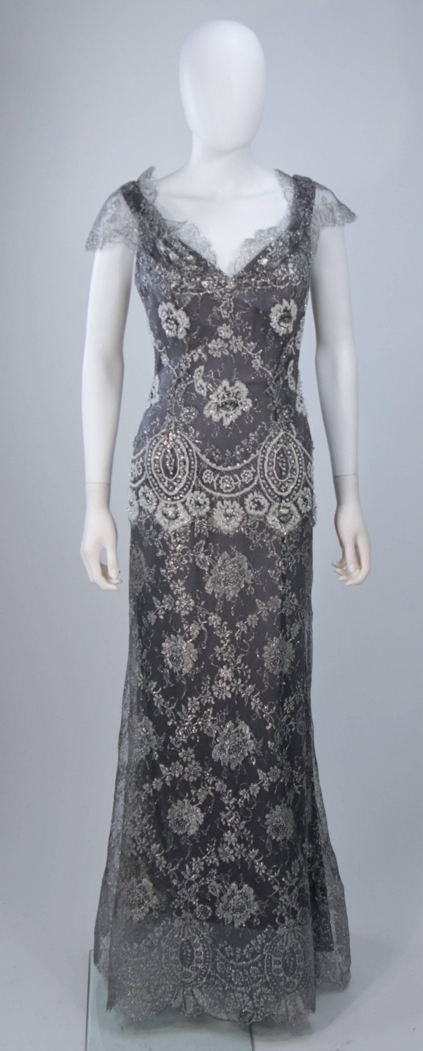  This Fe Zandi  gown is composed of a silver lame lace with scalloped edges. Features a draped neckline with sheer sleeve. There is a center back zipper closure, horse hair hem, and silk lining. In excellent vintage condition. 

**Please