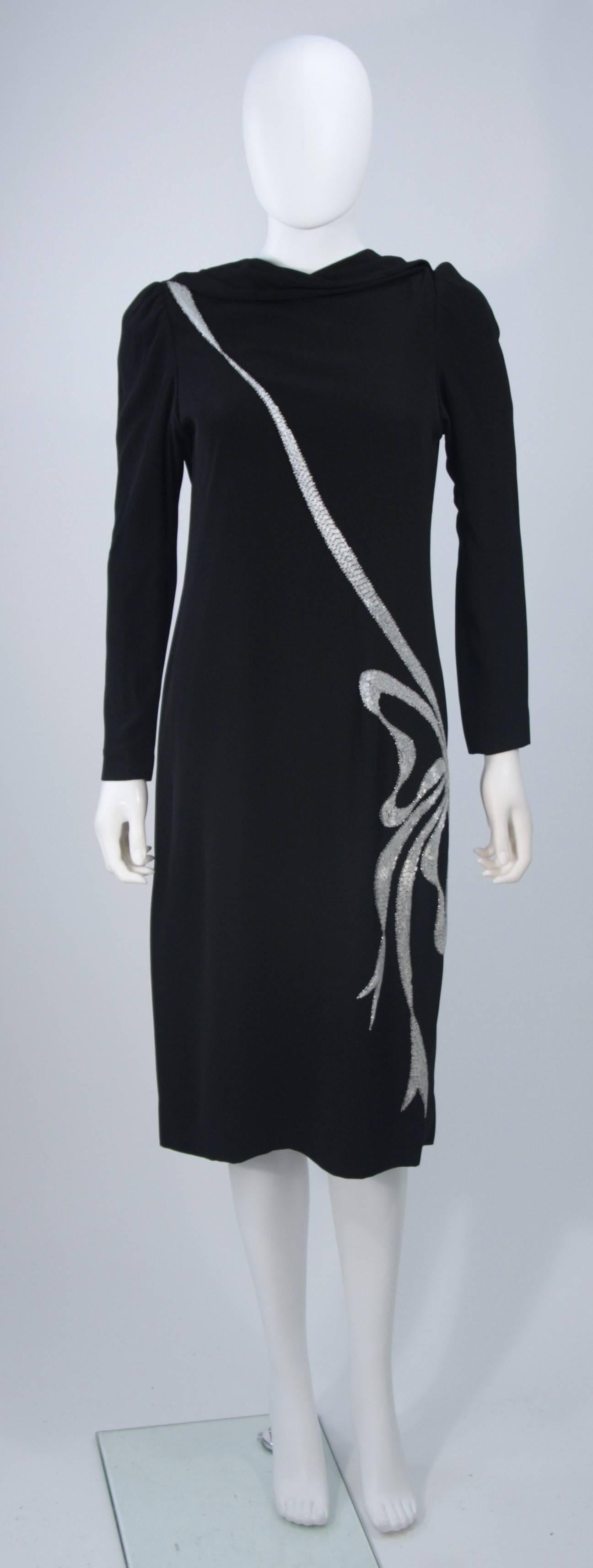  This Bob Mackie cocktail dress is composed of a black silk and features a beaded bow applique. There is an open back design with draping from the neck. Center back zipper closure. In excellent vintage condition. 

**Please cross-reference