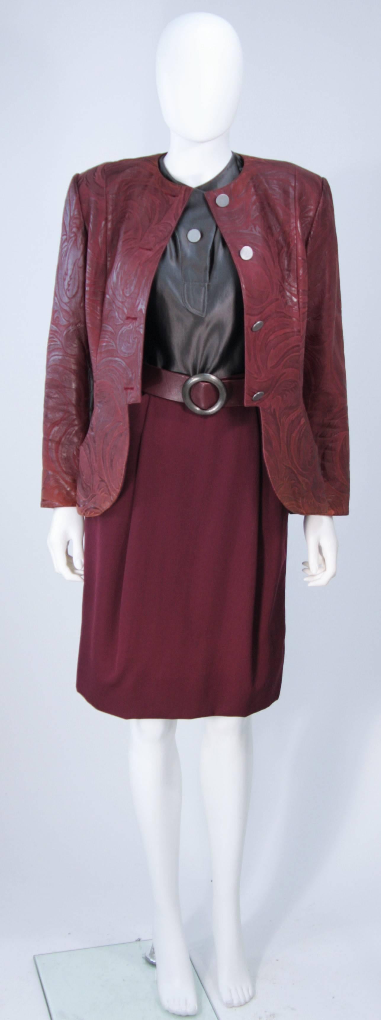  This Geoffrey Beene skirt suit is composed of a burgundy embossed leather jacket, leather belt and wool skirt, with grey satin blouse. the jacket has center front button closures.. The skirt is a classic pencil style with zipper closure. In