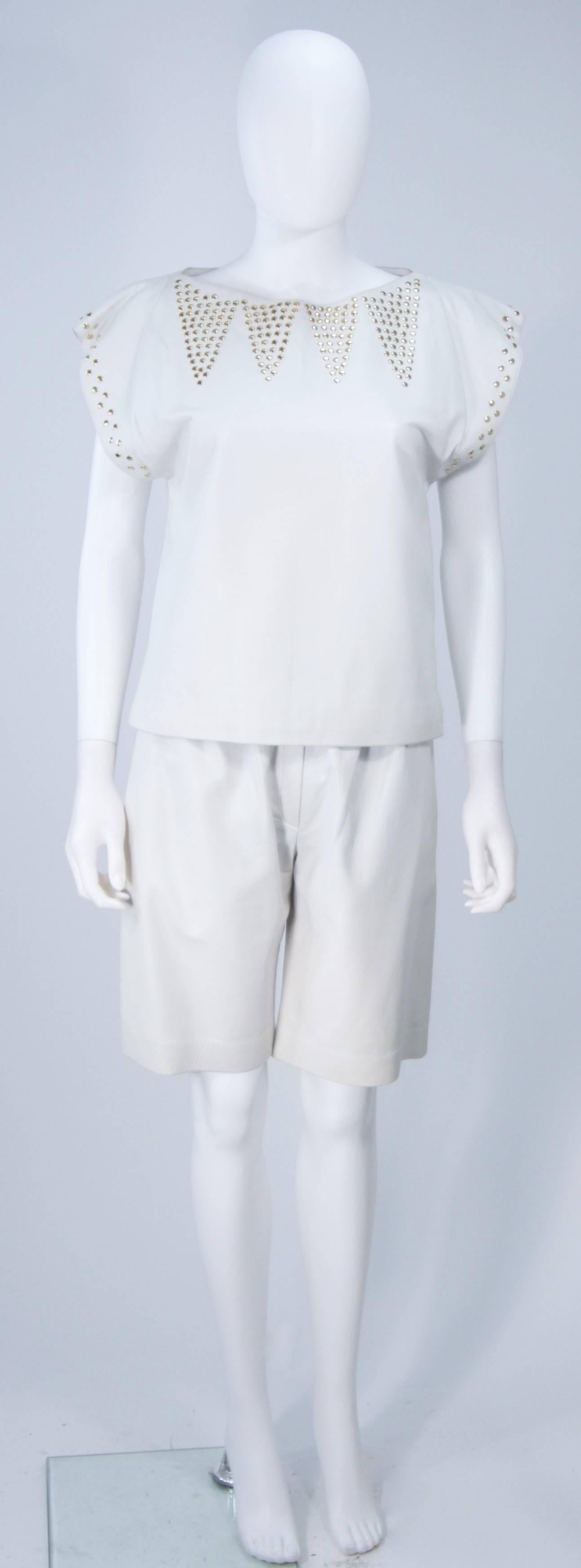  This Ted Lapidus short set is composed of an off white leather with gold studs. The blouse is a pull over style. The shorts feature a pleated front, side pockets, and zipper closure. In excellent vintage condition.

**Please cross-reference
