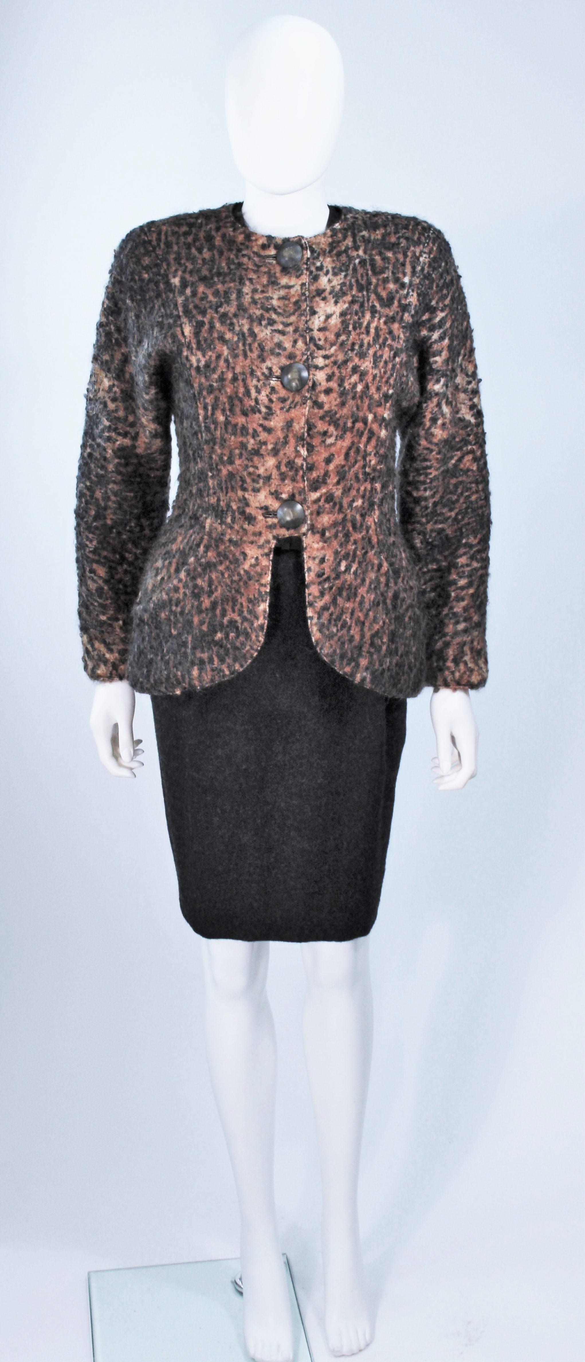  This Geoffrey Beene ensemble is composed of a printed mohair jacket, brown silk blouse and belt, as well as a grey wool pleated skirt. The skirt features front pleating and side pockets, with a center back zipper closure. The mohair coat has center