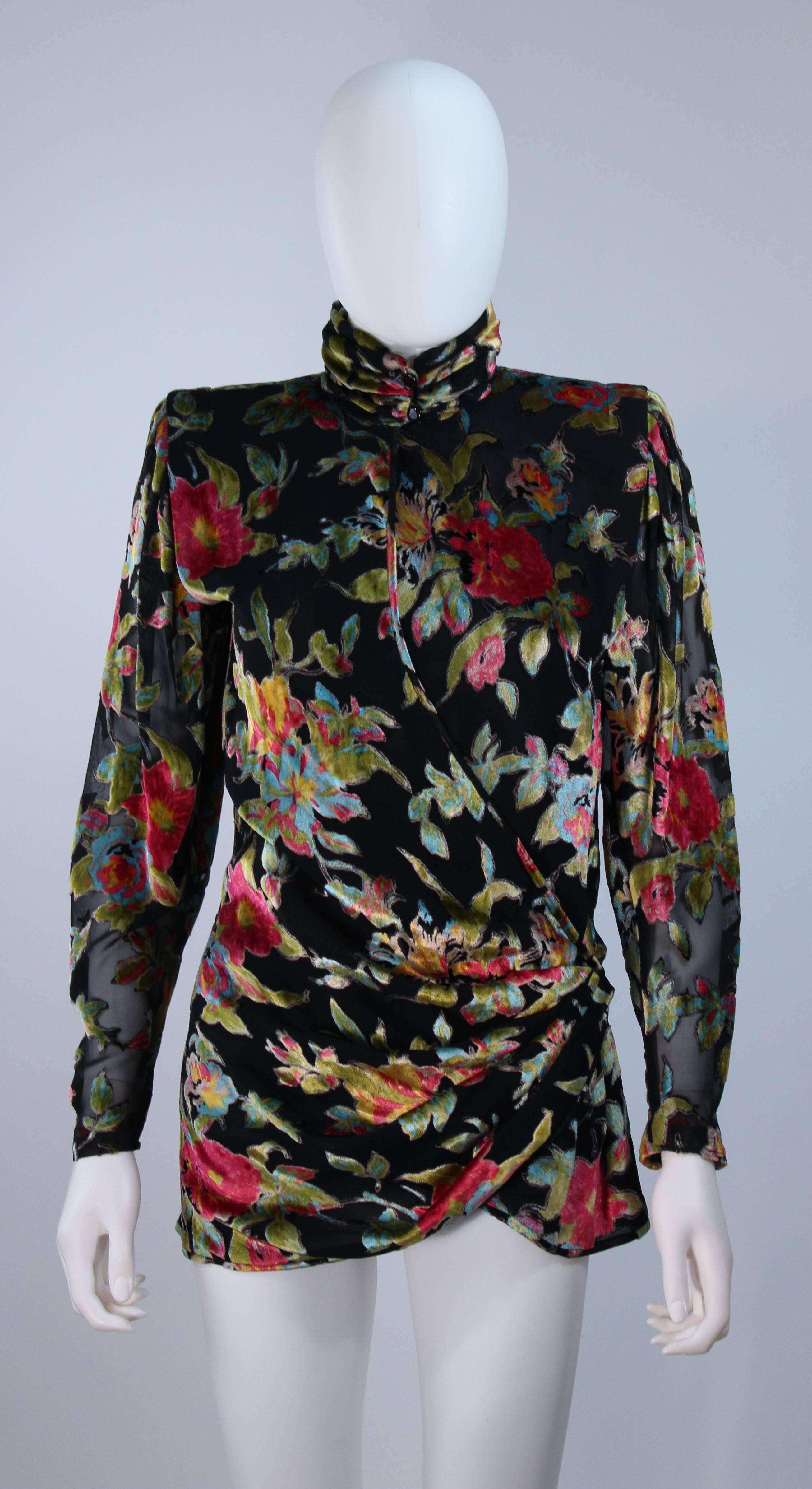  This Ungaro blouse is composed of a silk chiffon and velvet combination with a floral motif in hues of reds, greens, and blues. Features a mock style neckline with center front closures and interior tie. In excellent vintage condition. 

 