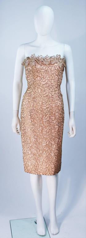  This cocktail dress is composed of a pink floral applique fabric with gold detailing. There is a center back zipper, features interior bustier foundation with boning. In excellent vintage condition with original tags. 

  **Please cross-reference