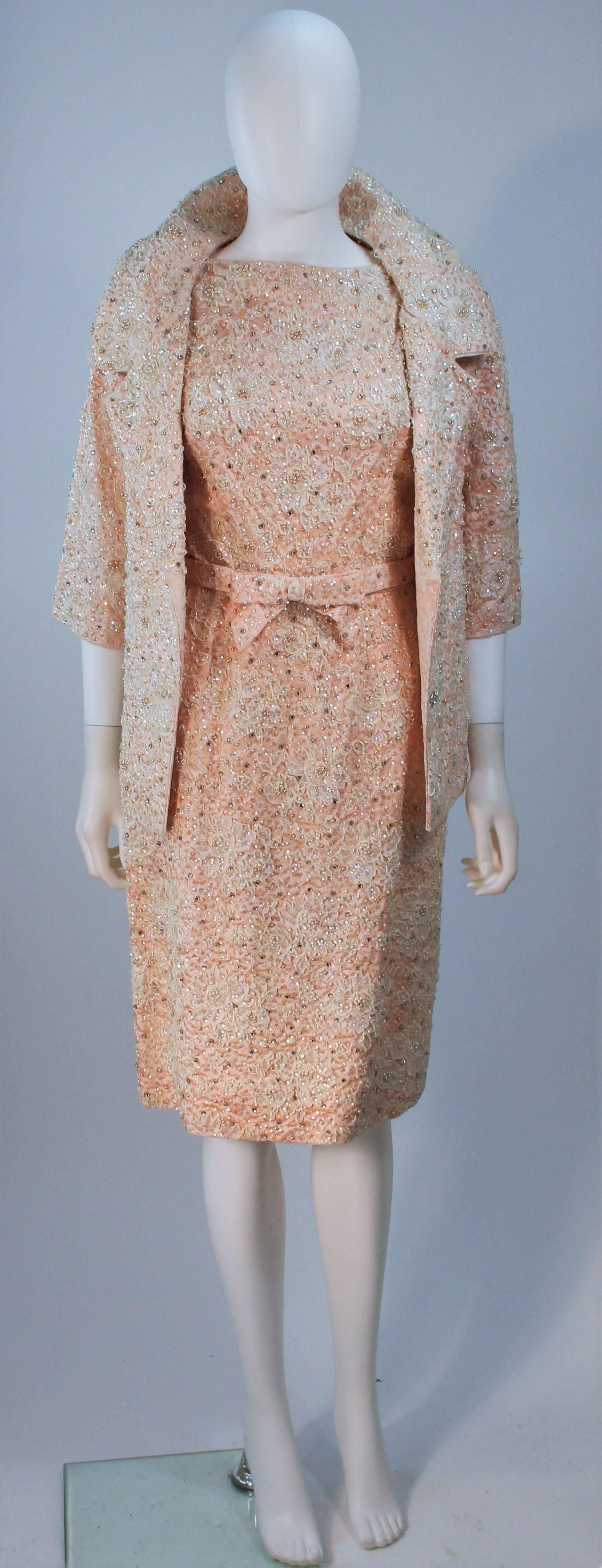  This Haute Couture Internationale  ensemble is composed of a beaded pink lace combination. Features a classic style dress, short jacket with center front rhinestone buttons, and a stylized belt. In excellent vintage condition with original tags.