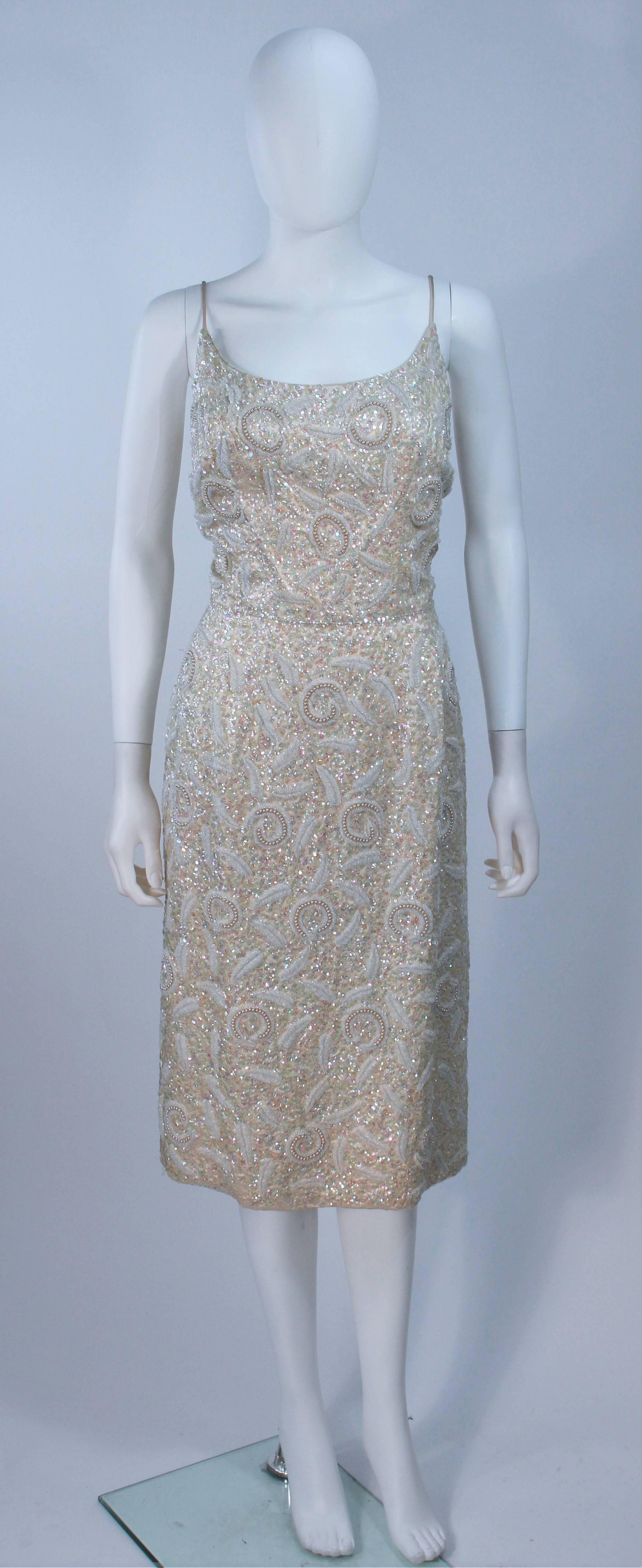  This cocktail dress is composed of an off white silk and is embellished with iridescent sequins. The  spaghetti strap design features a center back zipper closure. In excellent vintage condition with original tags. 

  **Please cross-reference