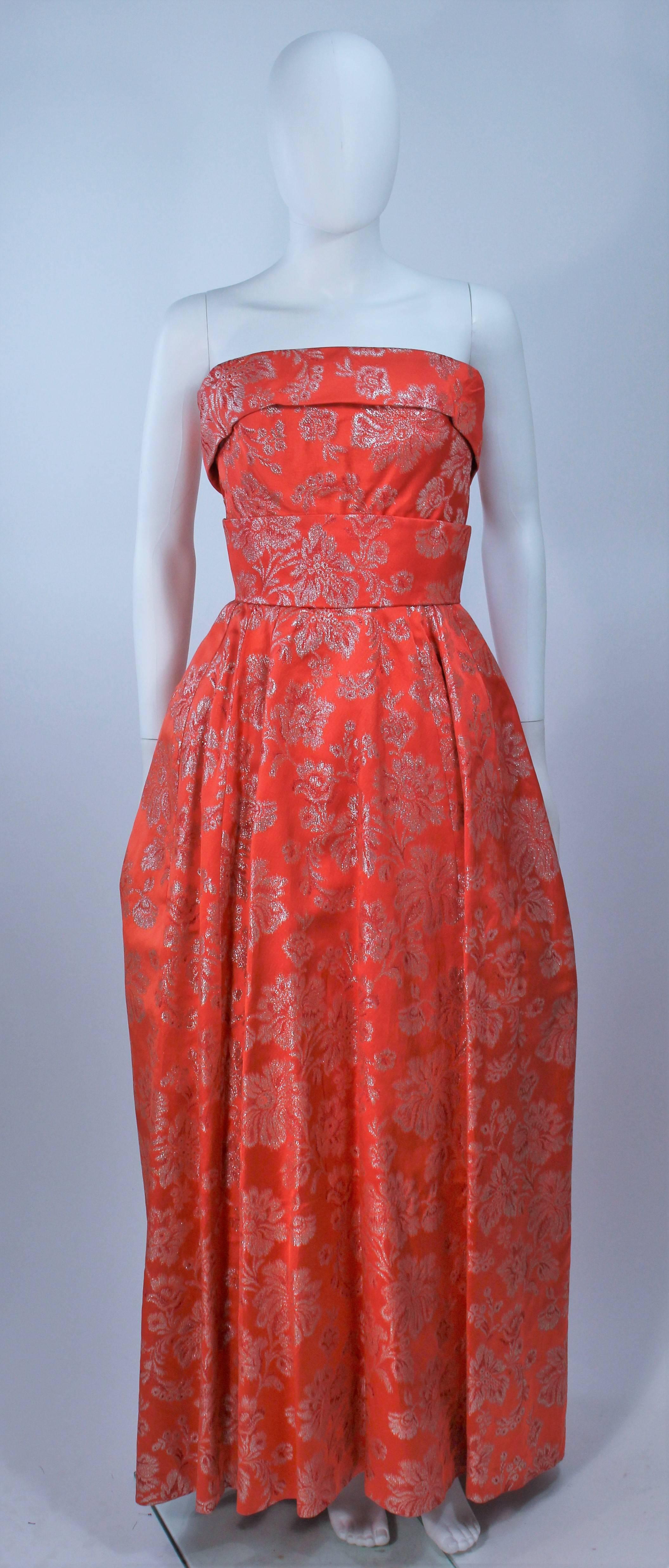  This gown is composed of a coral hue orange silk with floral lame motif. There is a large bow detail at the center back and a zipper closure. There is interior boning and bustier foundation (Shoot with additional crinoline). In excellent vintage