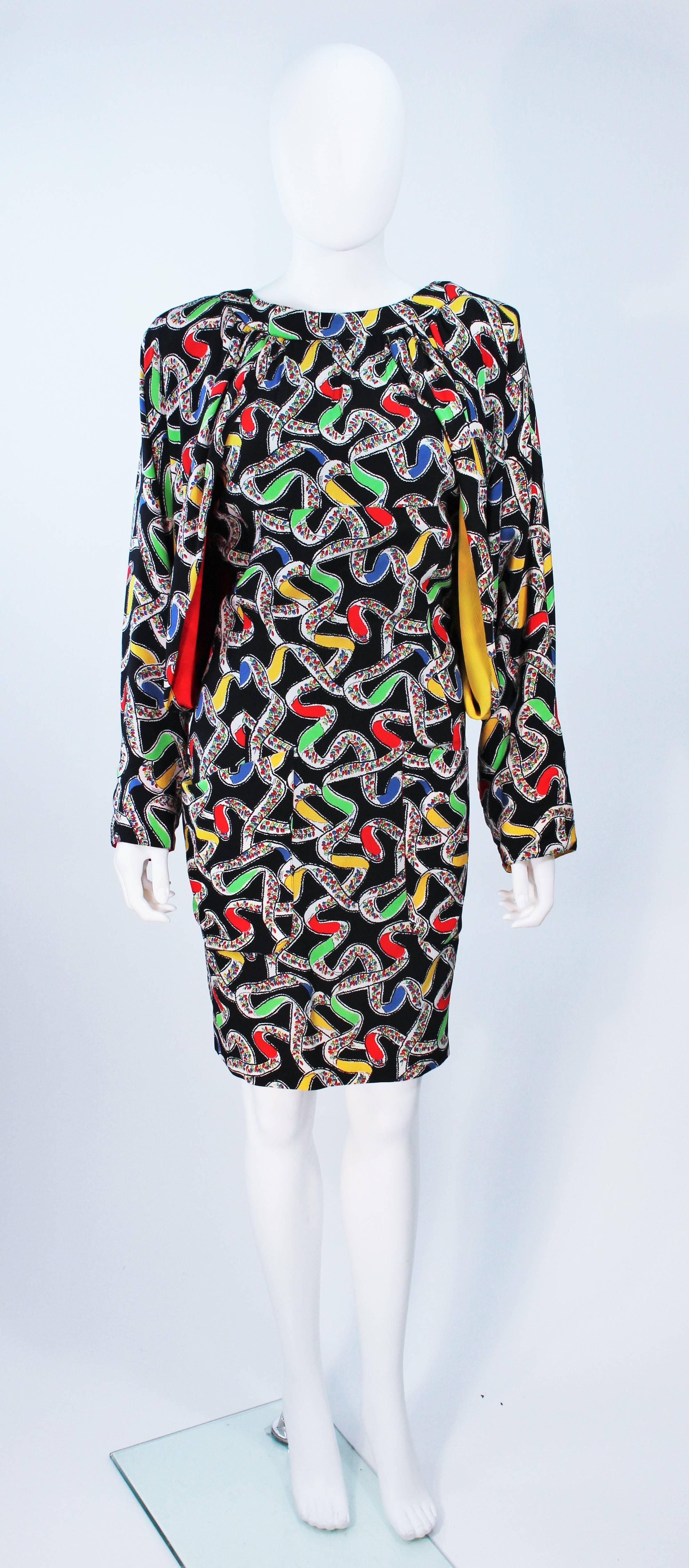  Dieser Karl Lagerfeld zugeschriebene Entwurf  das Kleid besteht aus schwarzer Seide mit einem abstrakten Druck in einer Primärfarbengeschichte. Mit drapierten Ärmeln und einem Schlüsselloch im Rücken. Es gibt einen Reißverschluss in der Mitte des