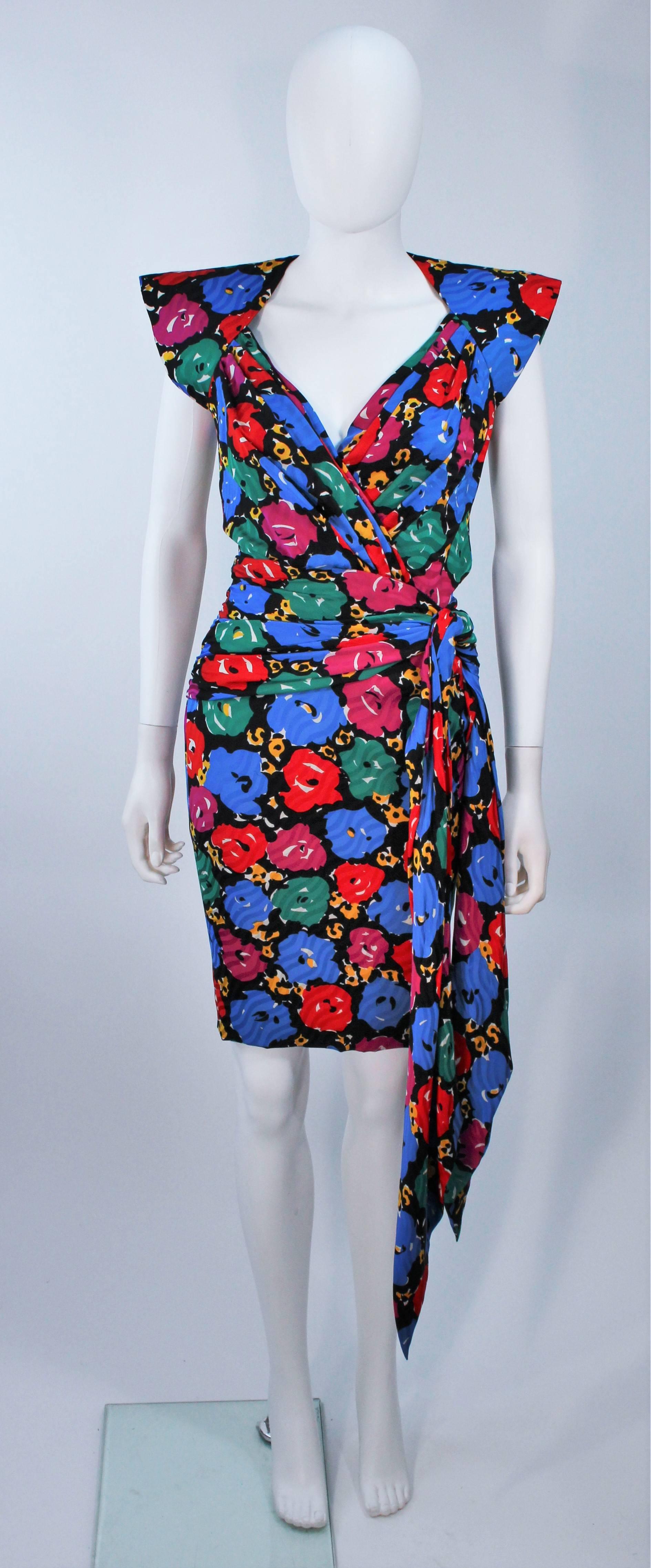  This Andrea Odicini cocktail dress is composed of a printed silk with floral print in a primary color story. Features structured shoulder with a side drape design. There is a center back zipper closure. In excellent vintage condition. 

 